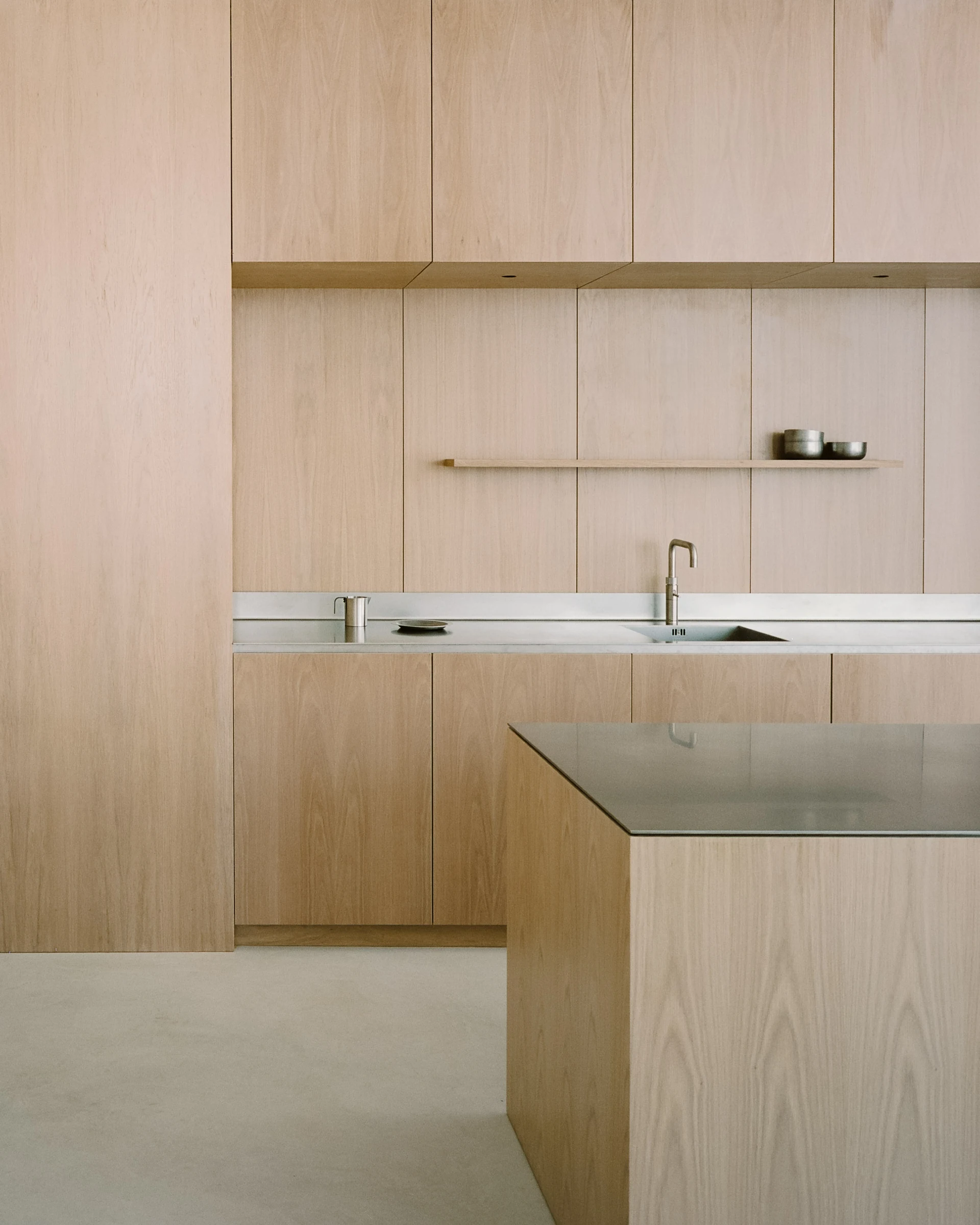 Cherry Orchard by Actual Office, photographed by Nick Dearden — Ash communal table and wishbone chairs set against a floor-to-ceiling wall of fine white voile curtaining: a thin linear LED pendant runs the length of the table, a slim glass and an open…