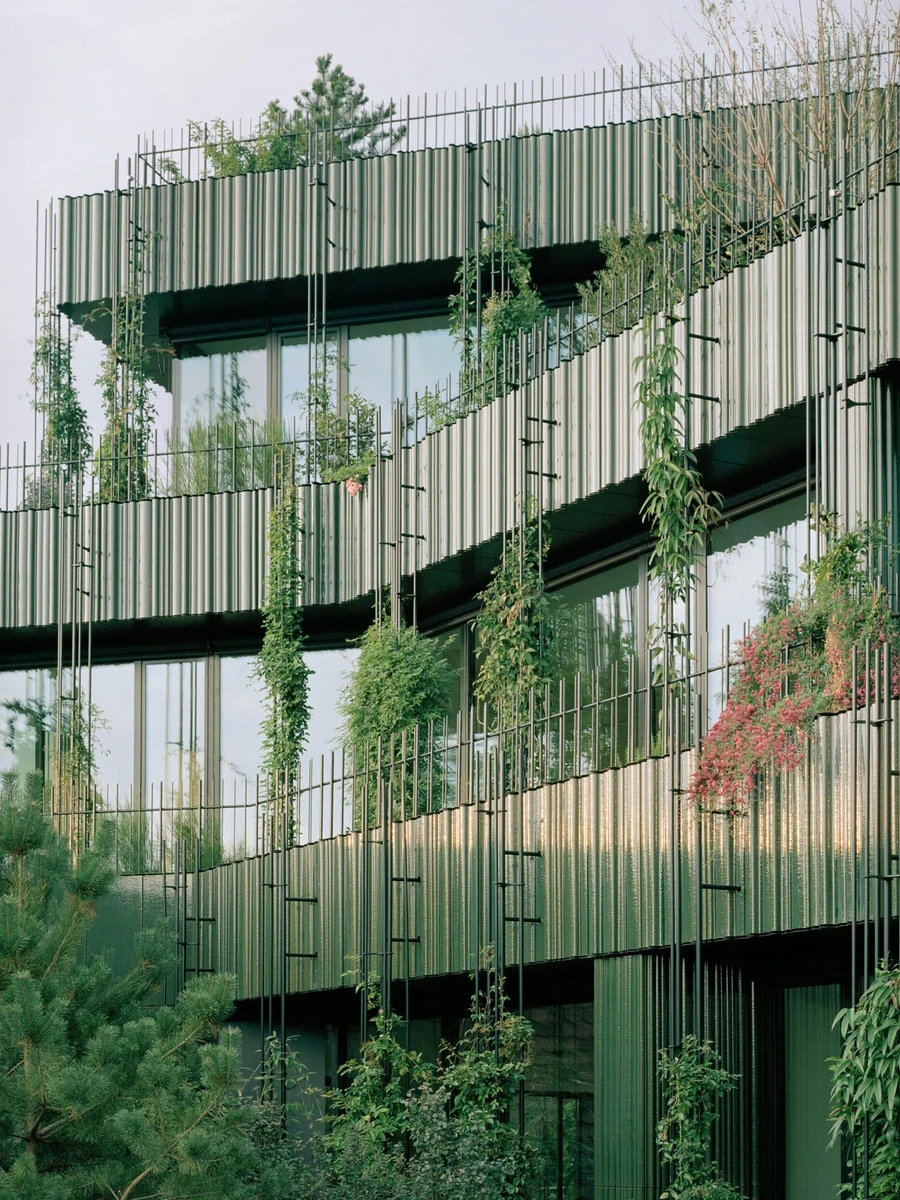 Globus, Basel by Miller & Maranta, photographed by Rory Gardiner — vertical fluted louvers in glazed green wrap stepped terraces as flowering vines cascade over their edges.