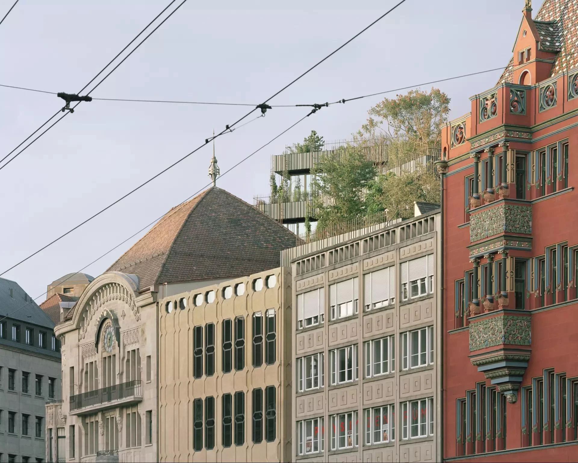 Globus, Basel by Miller & Maranta, photographed by Rory Gardiner — the Mittlere Brücke spans the Rhine below the old town, the green roof crown just visible among the gables.