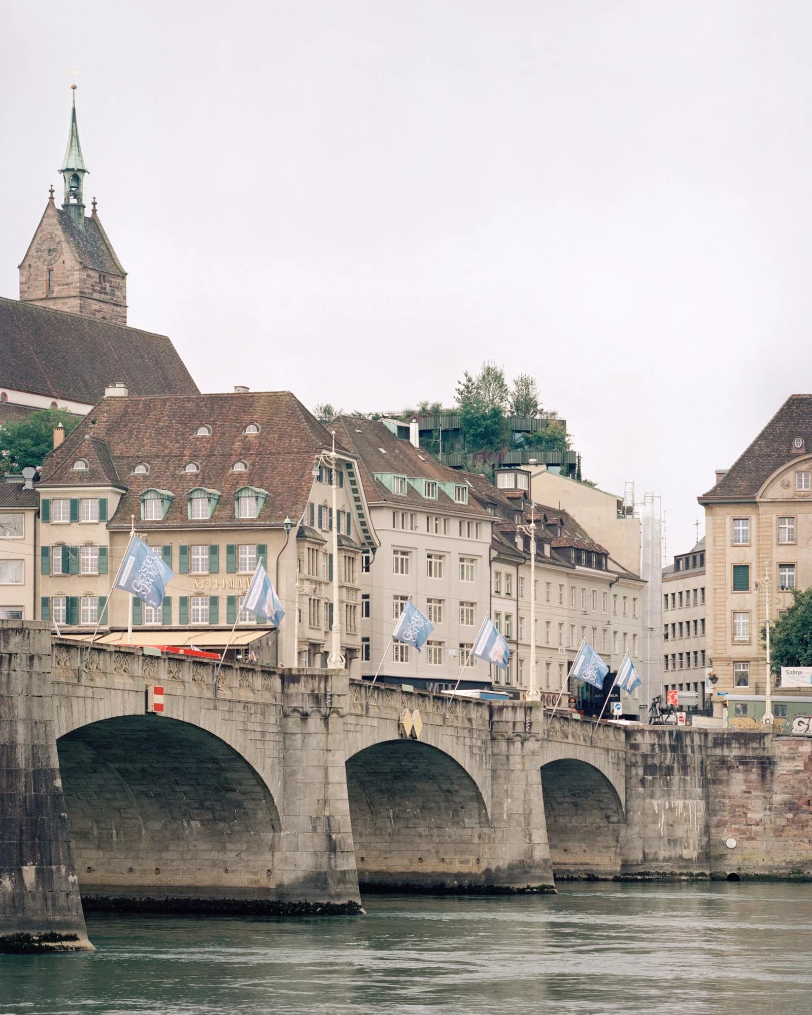 Globus, Basel by Miller & Maranta, photographed by Rory Gardiner — a view across the Rhine to Basel's old town roofline, the project reading as one volume among the historic facades.