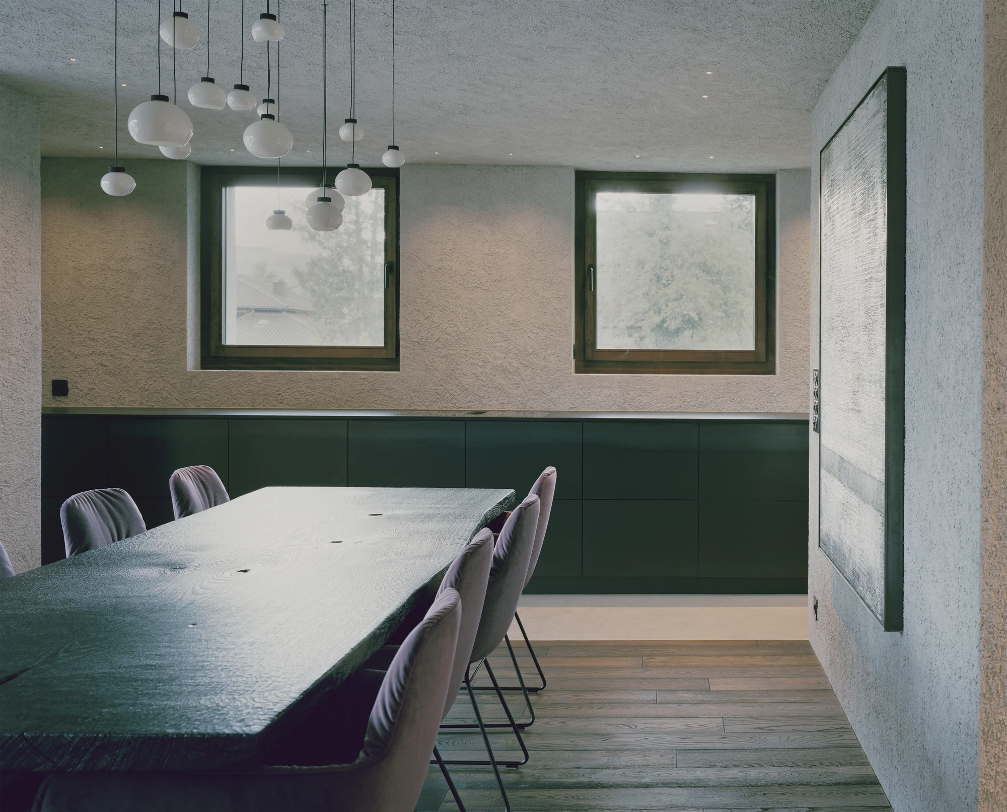 Tower house Vaduz by Schreiber Architekten, photographed by Barbara Buehler — velvet chairs gather at the dark table between two square spruce-framed windows set in plaster.