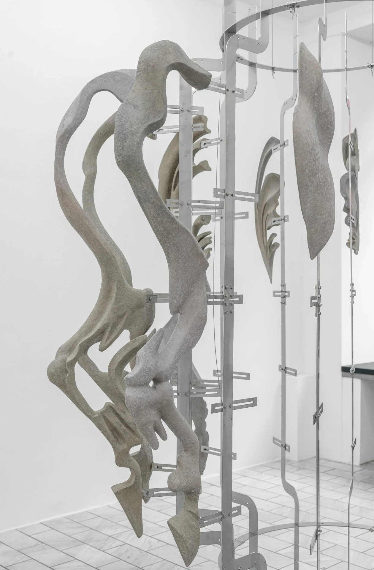 Double Star by Paola Siri Renard, photographed by Dirk Tacke — tall vertical fragments unfurl like torn limbs along the steel armature, anatomy fraying into ribbon-like extensions above the marble floor.