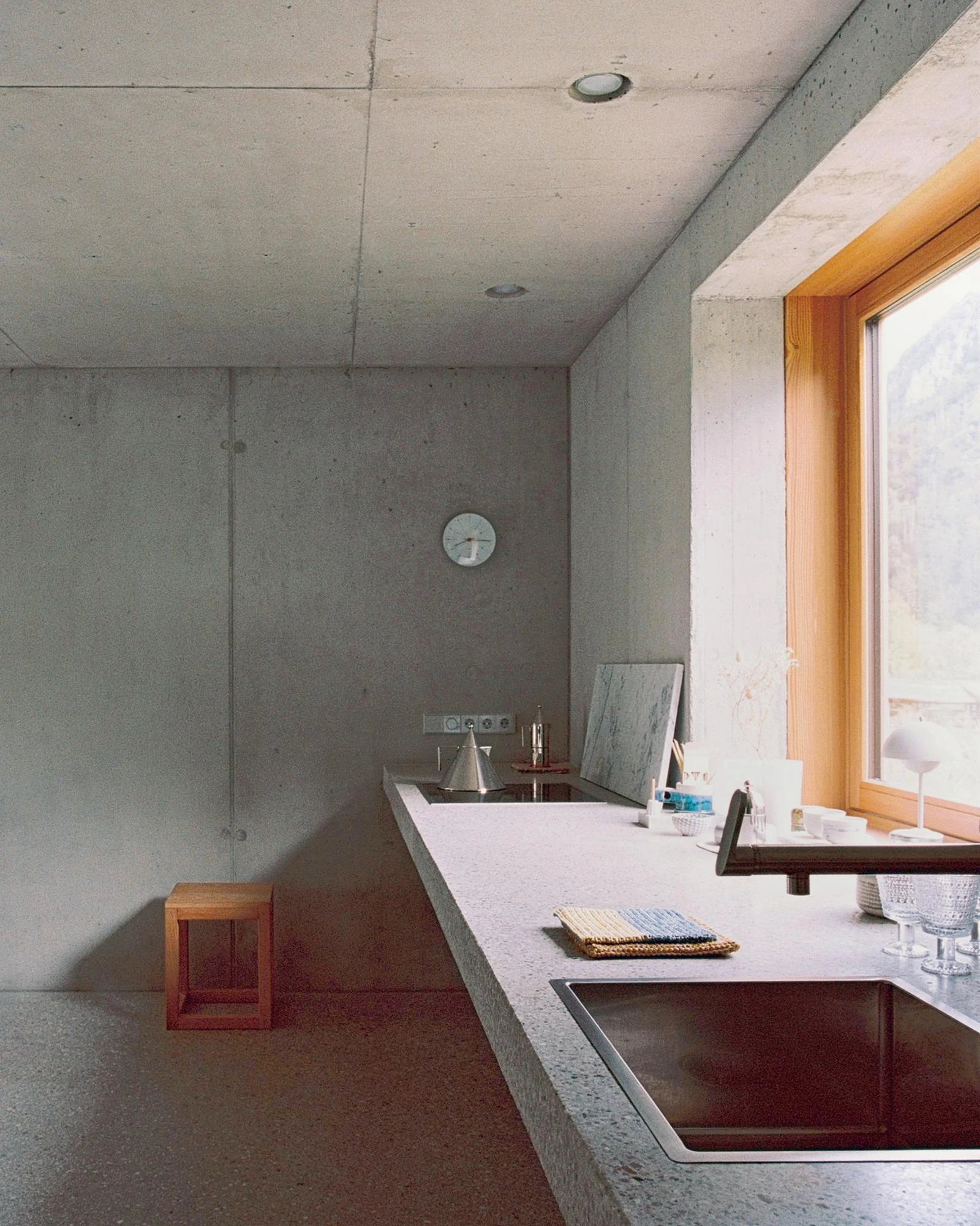 House Alva by Arhitekti Počivašek Petranovič, photographed by Urban Petranovič — The kitchen counter cast in terrazzo-flecked concrete with an inset sink, set against bare concrete walls and a larch-framed window.