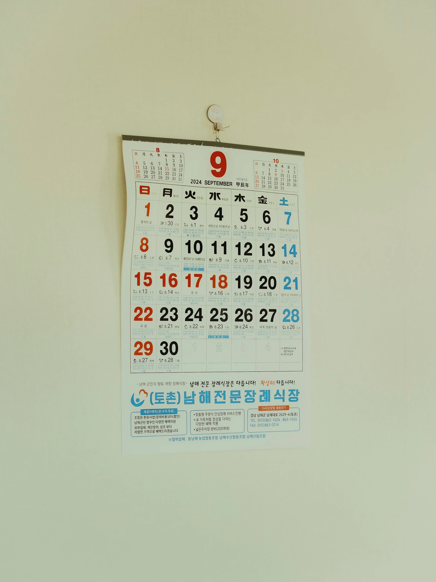 Nirvana by Daesung Lee, photographed by Daesung Lee — A wall calendar turned to September, printed with a Korean funeral home advertisement, hangs alone on a bare cream wall.
