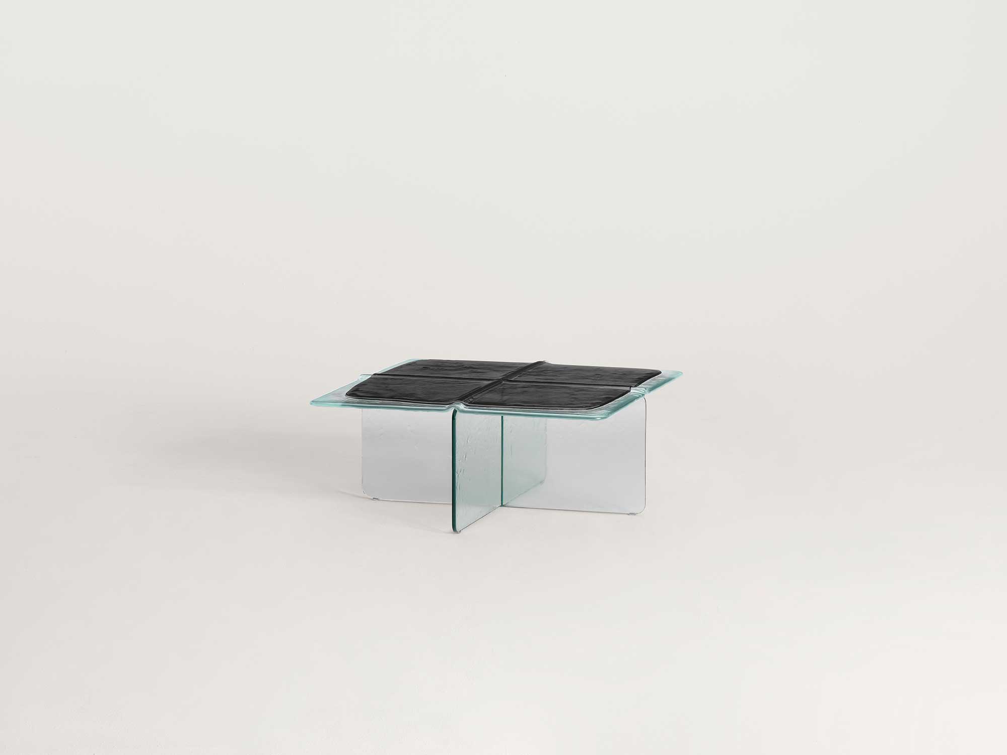 Glacier by Patricia Urquiola — Top-down detail of the blue table's seam meeting a vertical glass support, the deep-blue cast surface broken by the clear extra-light fin rising beneath it.