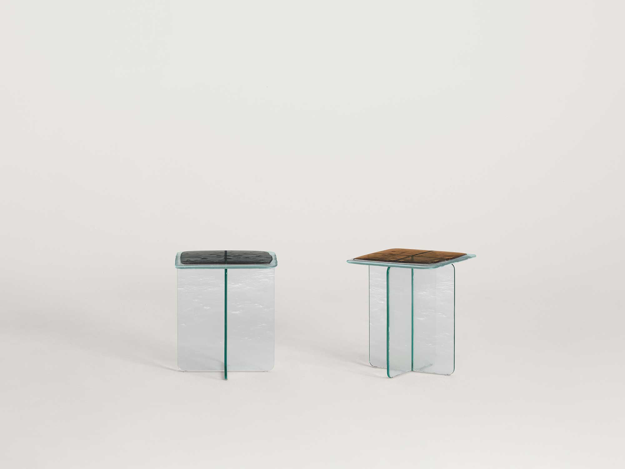 Glacier by Patricia Urquiola — Corner detail of the black Glacier table: four dark fused tiles with a rippled overhanging rim sit on the thick, faintly frosted extra-light glass base.