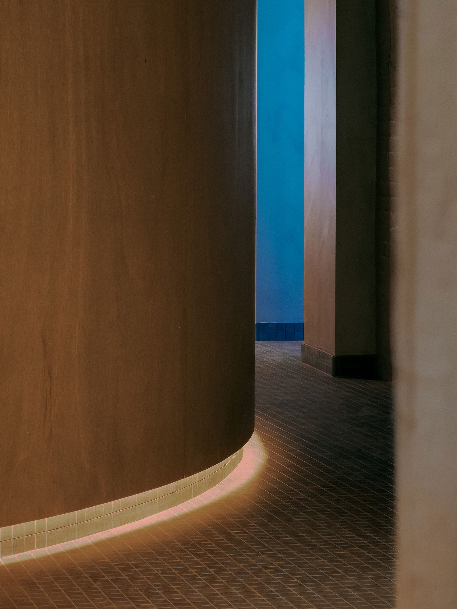 Recess by Future Simple Studio, photographed by Félix Michaud, Recess — A circular backlit panel of rippling blue light hangs behind sheer curtains in the dim lounge, low side tables and seating in silhouette.