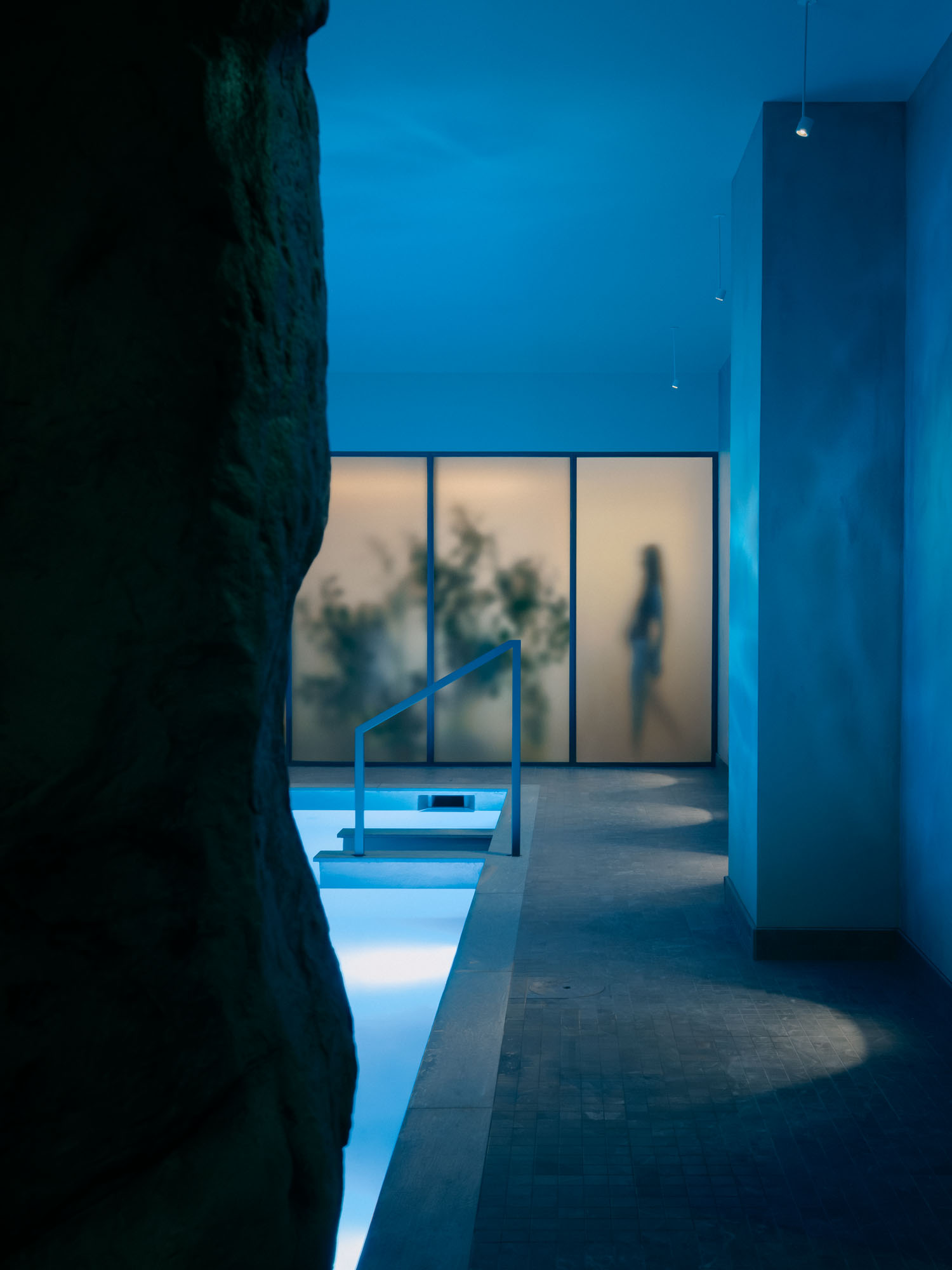 Recess by Future Simple Studio, photographed by Félix Michaud, Recess — A lone bather sits on the tiered pine benches of the round sauna, backlit vertical slots glowing around the ring beneath the domed ceiling and oculus.