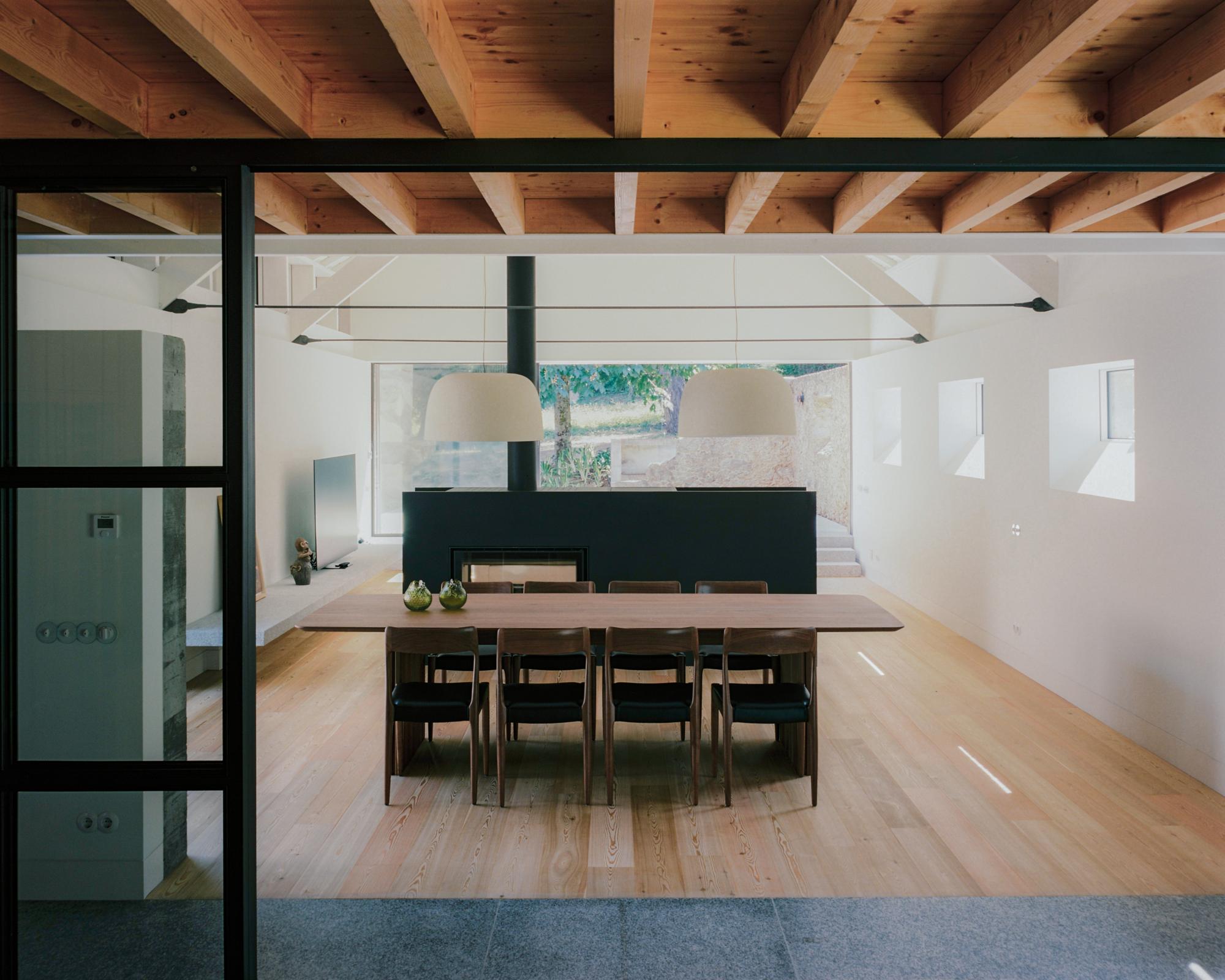 Single-Family Home by Branco del Rio Arquitectos, photographed by Frederico Martinho — A barrel-vaulted plaster corridor curves toward an overhead skylight, built-in pale timber wardrobes lining one side above a timber floor, a single armchair at the…