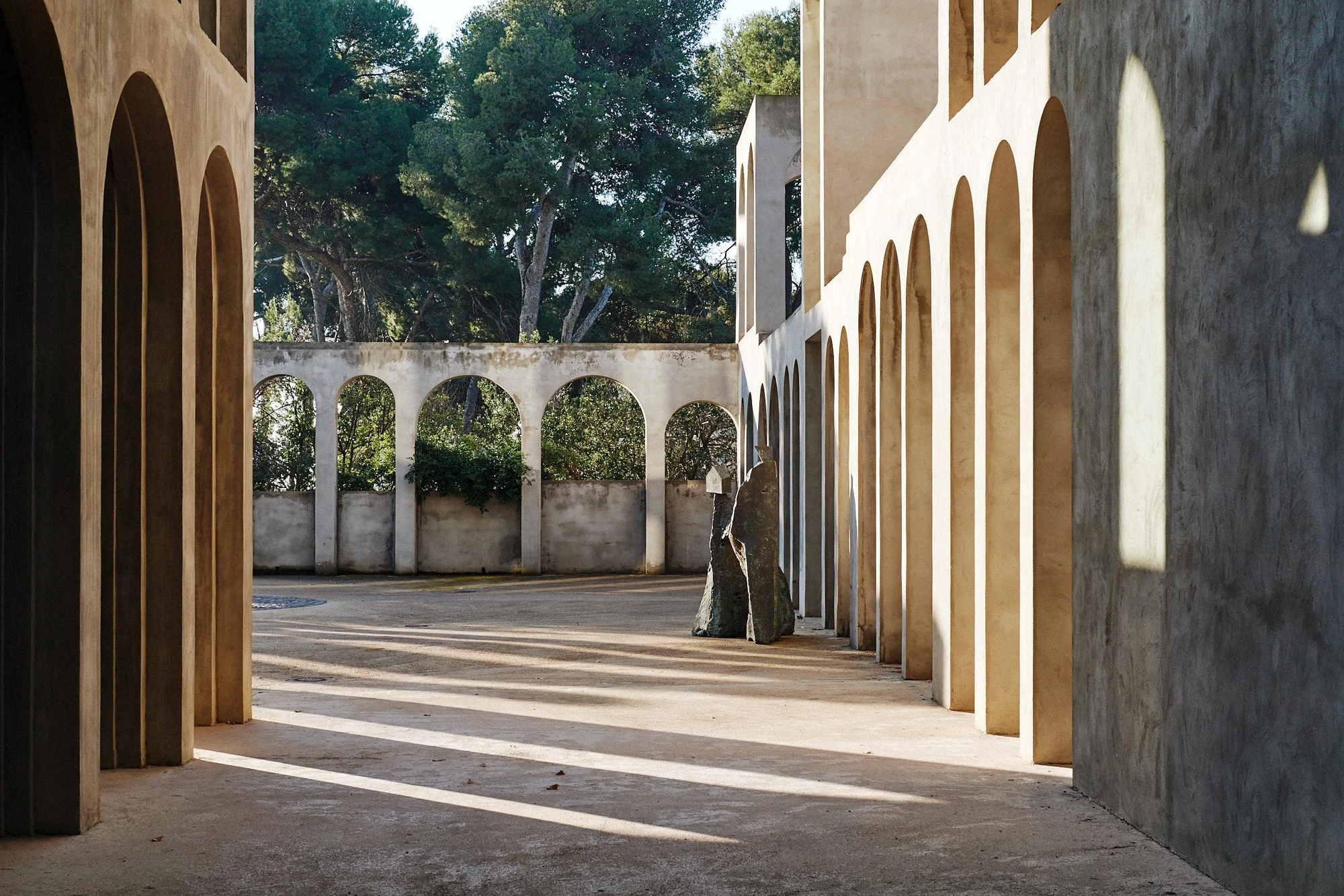 Xavier Corberó House and Studio by Xavier Corberó, photographed by Daniel Schäfer — A warm pink-plaster passage of nested arches leads up a short flight of steps to a lone figure standing beside a timber door.