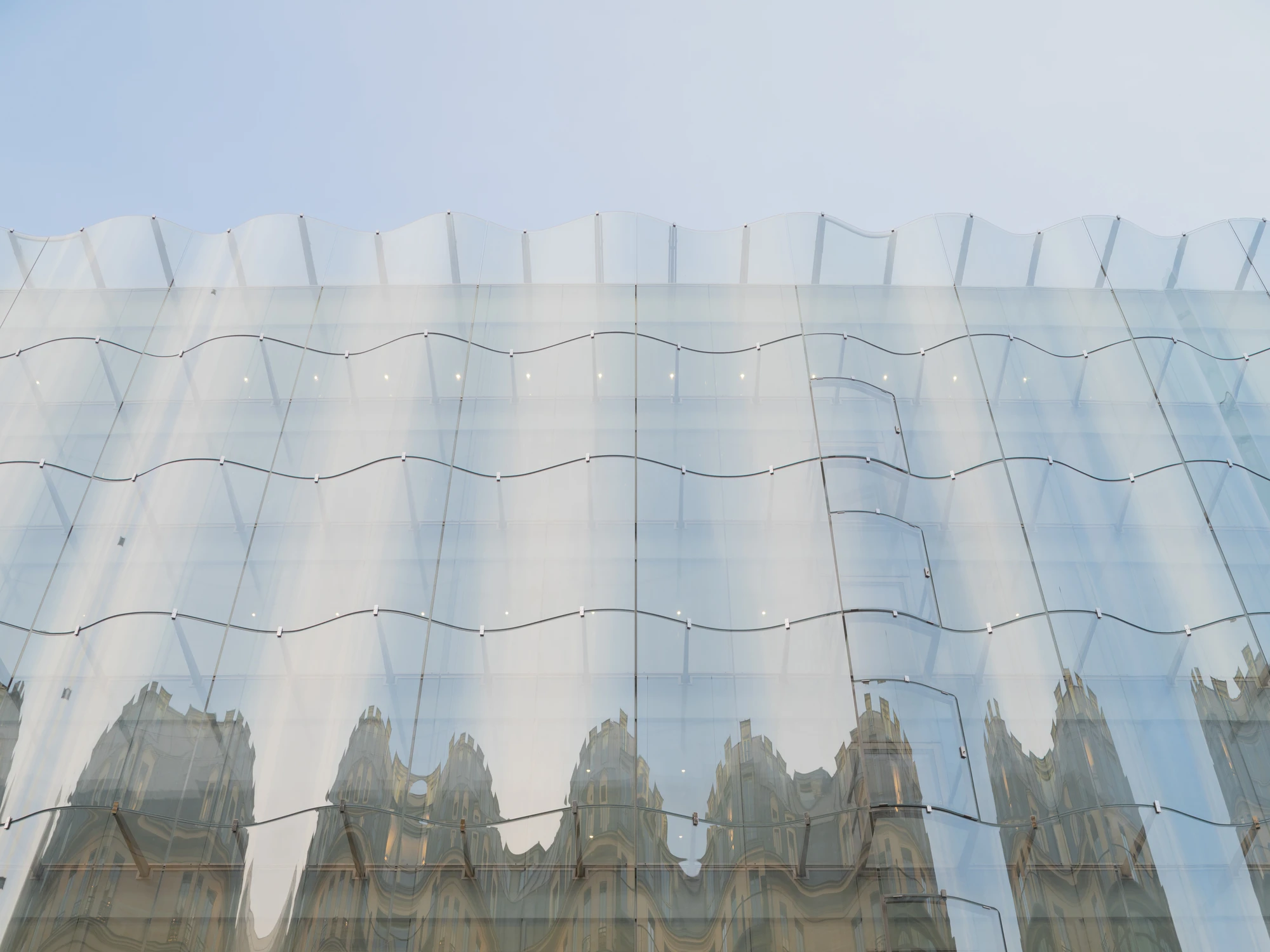 La Samaritaine by SANAA, photographed by Jared Chulski — A close read of the facade: horizontal cables and steel clips hold each wave of glass, Haussmann rooftops rippling in the reflection.
