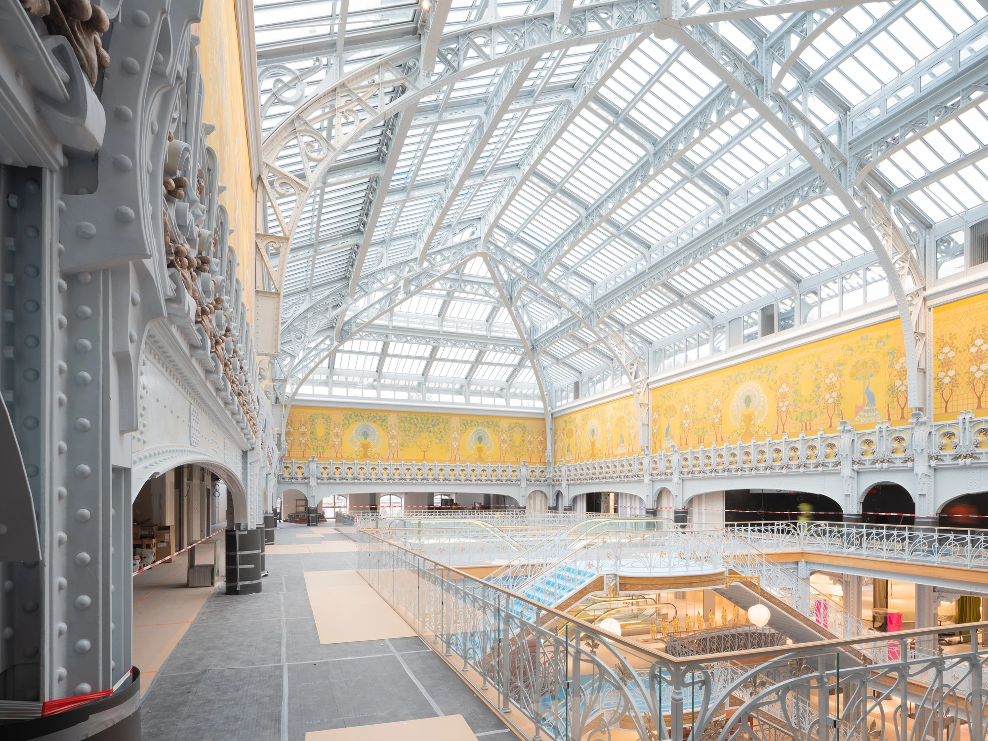 La Samaritaine by SANAA, photographed by Jared Chulski — The great Art Nouveau hall under its glazed roof, the yellow peacock frieze running above pale ironwork.
