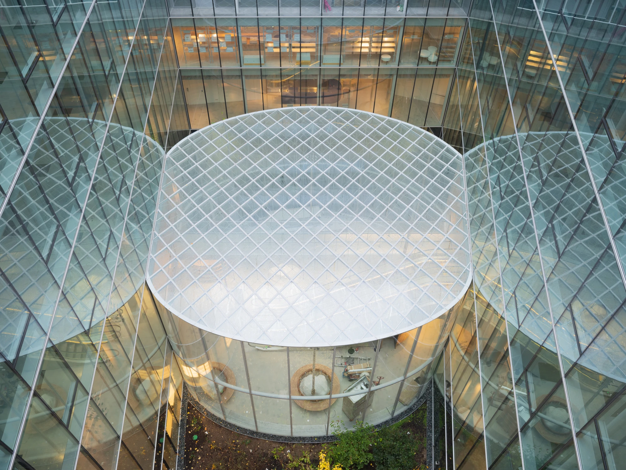 La Samaritaine by SANAA, photographed by Jared Chulski — Looking down into the glass cylinder courtyard, its top closed by a taut steel net over the void.