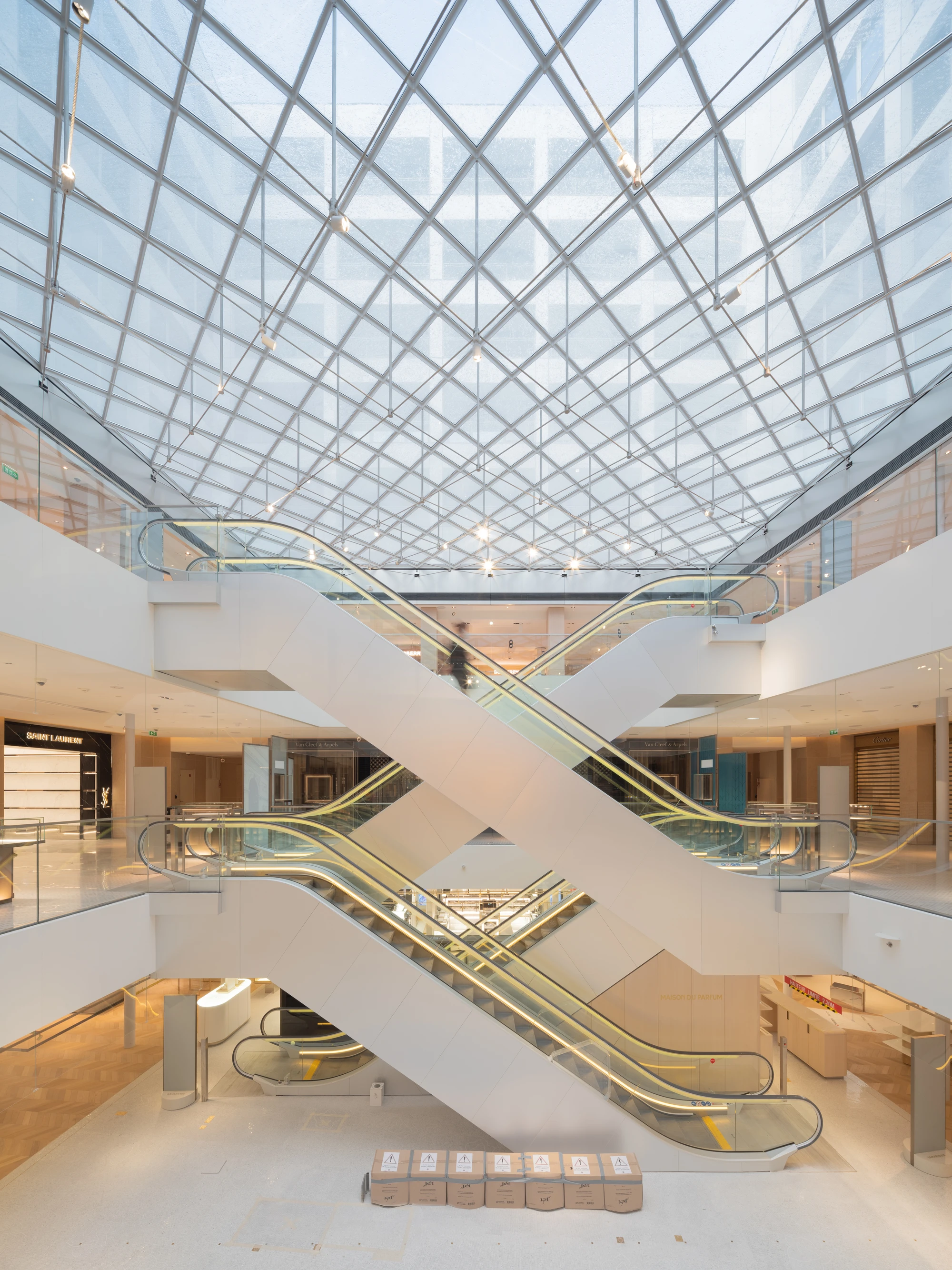 La Samaritaine by SANAA, photographed by Jared Chulski — Escalators scissoring in an X beneath a diagonal grid of glazing in one of the new courtyards.