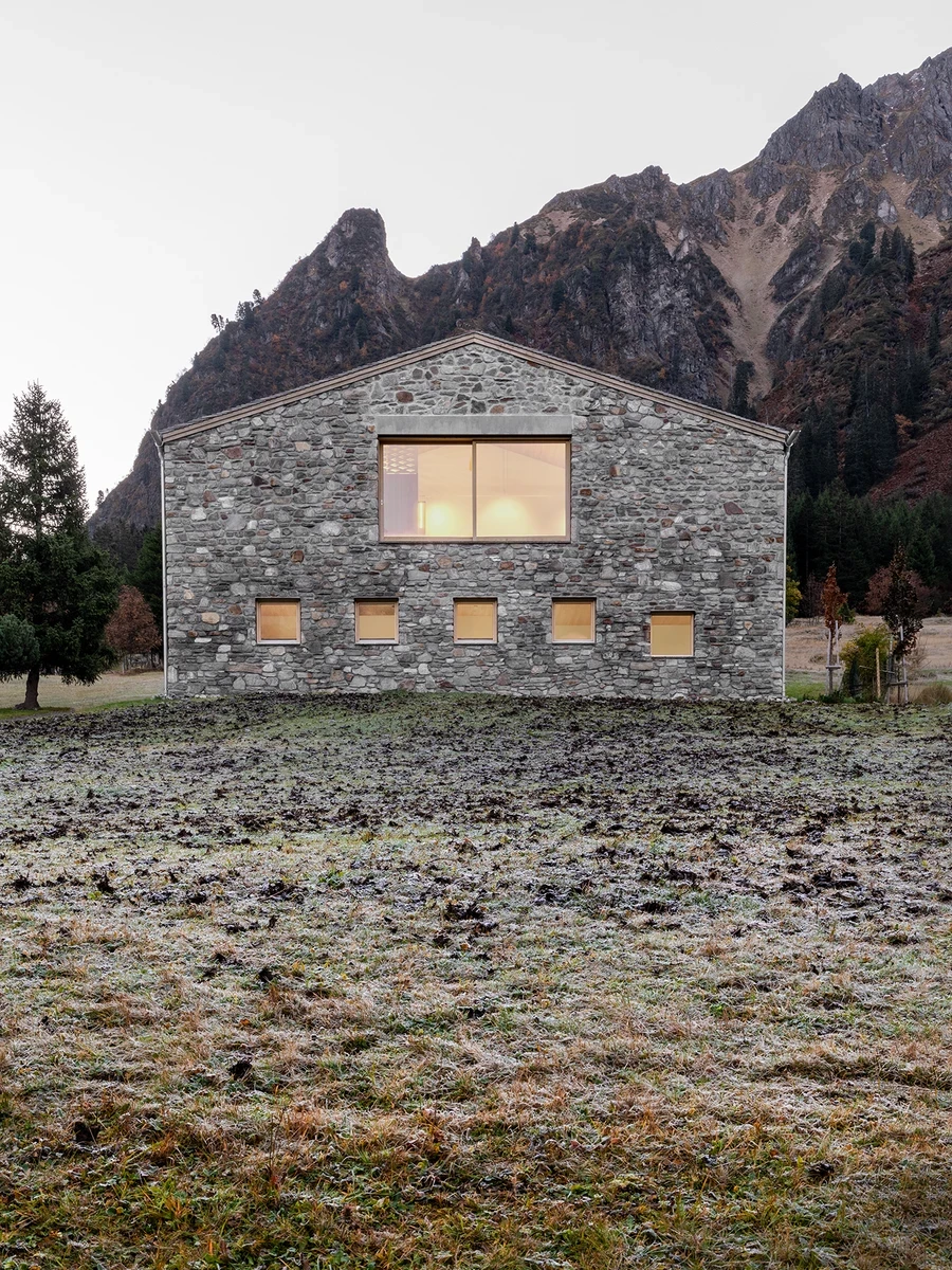 Vergalderie by Christian Tonko, photographed by Gustav Willeit — Across a frost-stiffened meadow, the gable end shows its hand-picked Montafon stone and a grid of small square openings