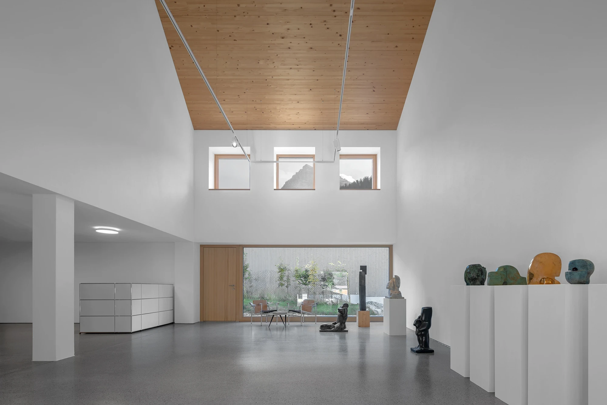 Vergalderie by Christian Tonko, photographed by Gustav Willeit — The double-height gallery in polished concrete, Herbert Albrecht's bronzes on white plinths beneath square clerestory windows cropping the peaks