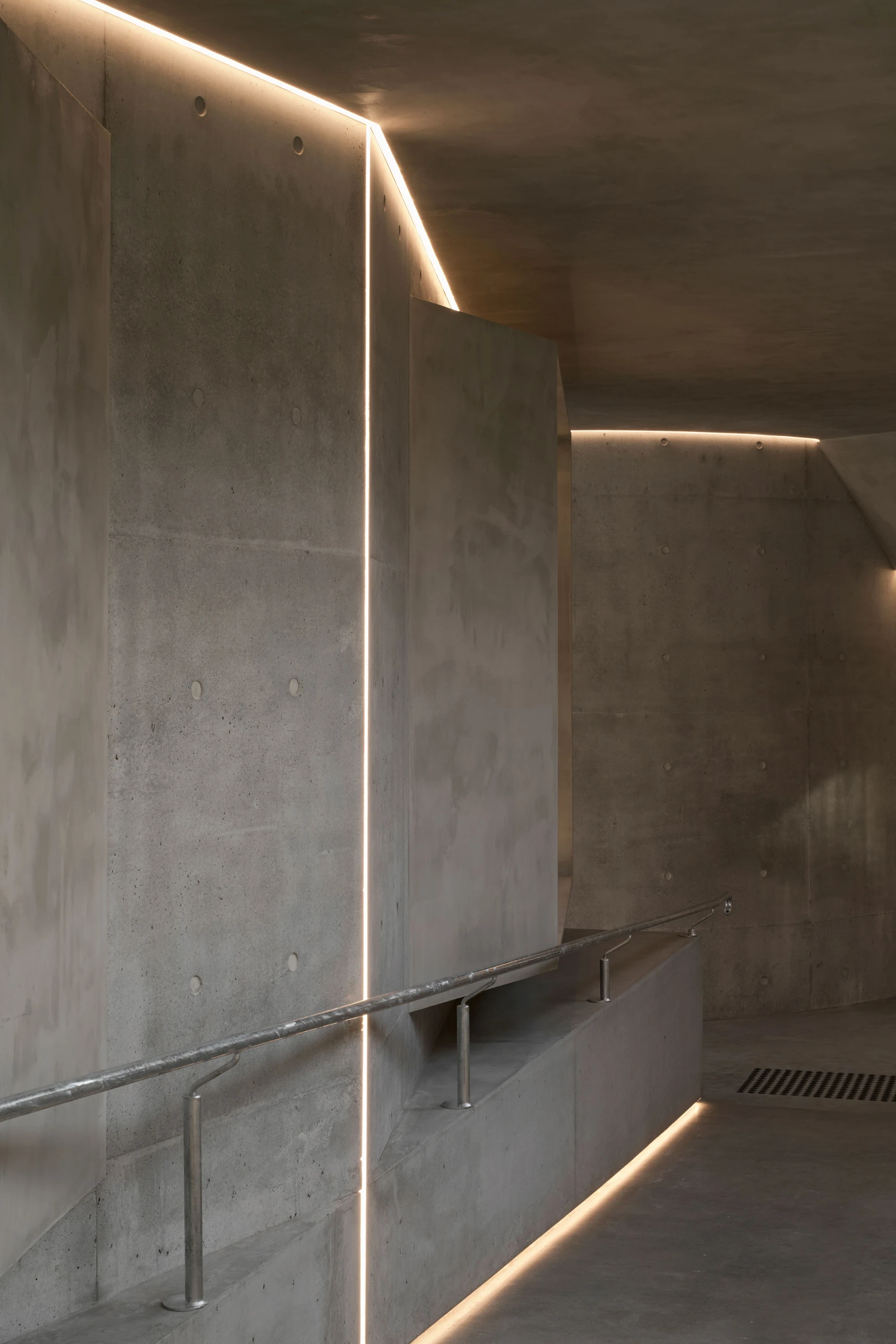 Gallery For A Tree Flyover Marcellin College by Farrell Wray Architects — Braybrook, Australia: continuous LED reveals tracing the cranked concrete wall and folded ceiling above the galvanised handrail.