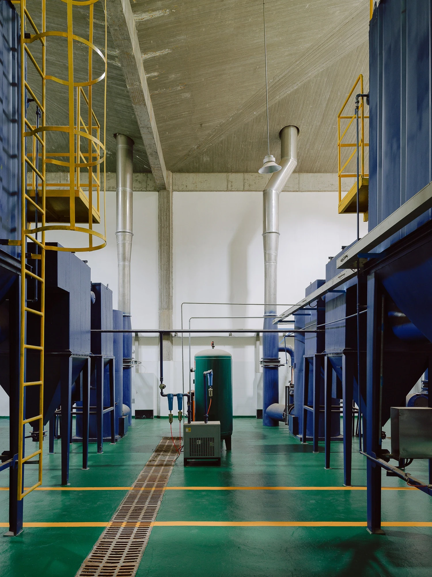 Suichang Funerary Complex by Untitled Architects, photographed by Tianzhou Yang — a plant room with blue tanks, silver ductwork and yellow ladders over a green resin floor.