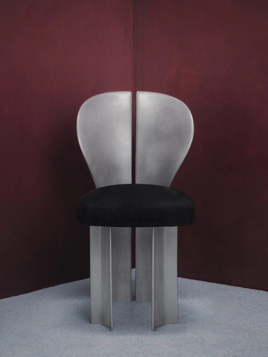 Lilium Chair by Studio NRG — a frontal view of the cast aluminium chair with its petal backrest, black suede seat, and scalloped column base.