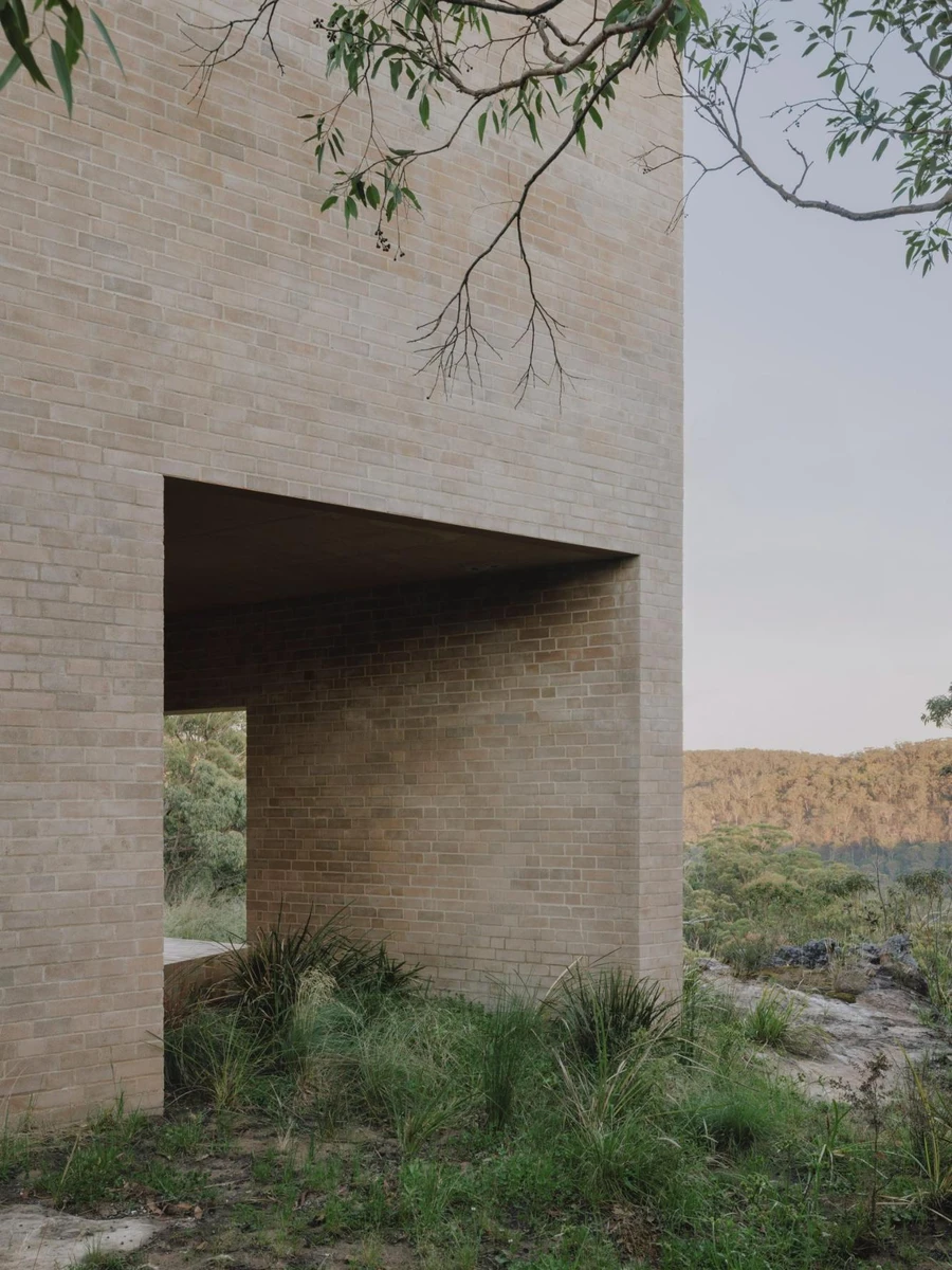 EA House, Southern Highlands by Bokey Grant, photographed by Clinton Weaver, the sand-toned brick volume seen through the eucalypt canopy, a perforated brick screen and deep window in its face.