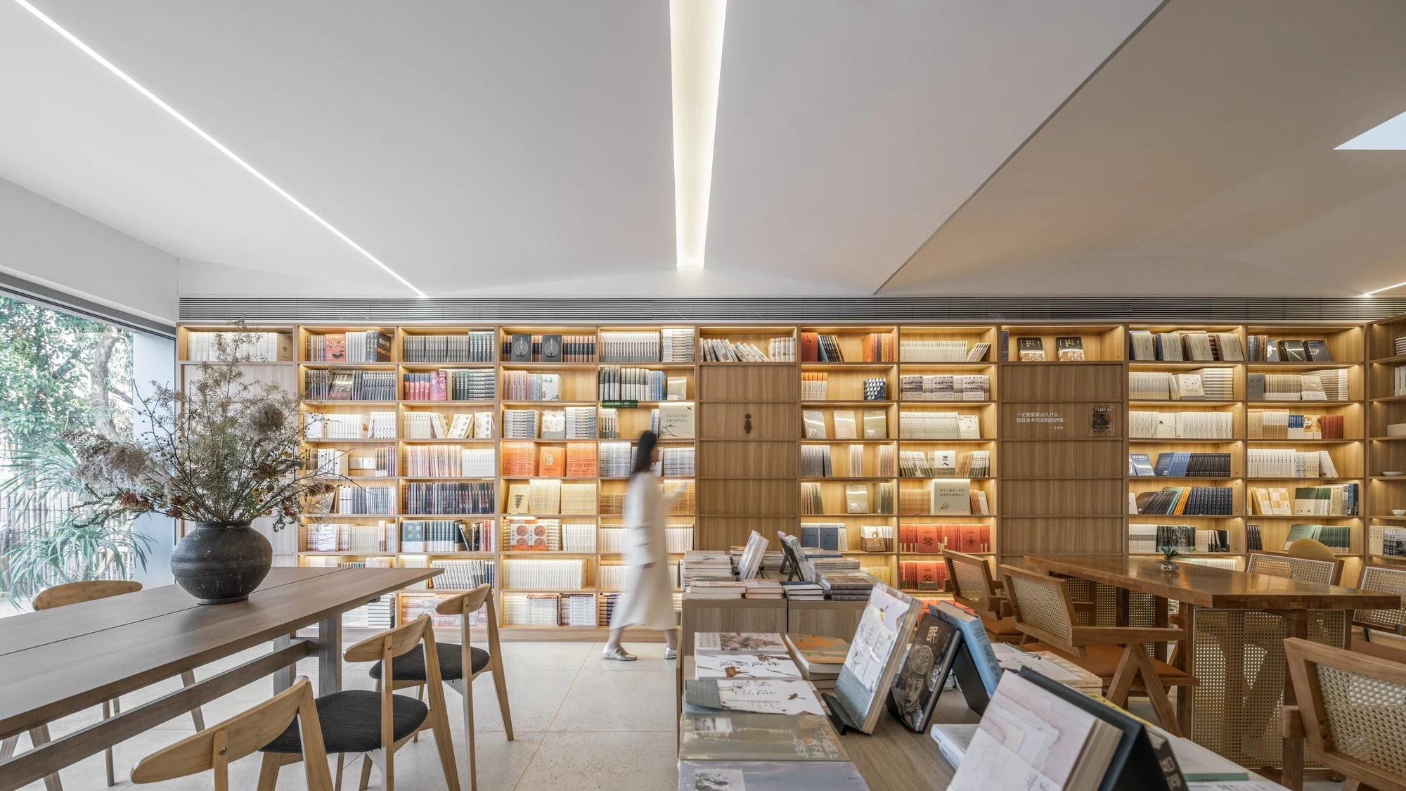 Heart Fields by Wutopia Lab, photographed by CreatAR Images — a linear skylight runs the length of the bookstore above backlit oak shelves lined with books.