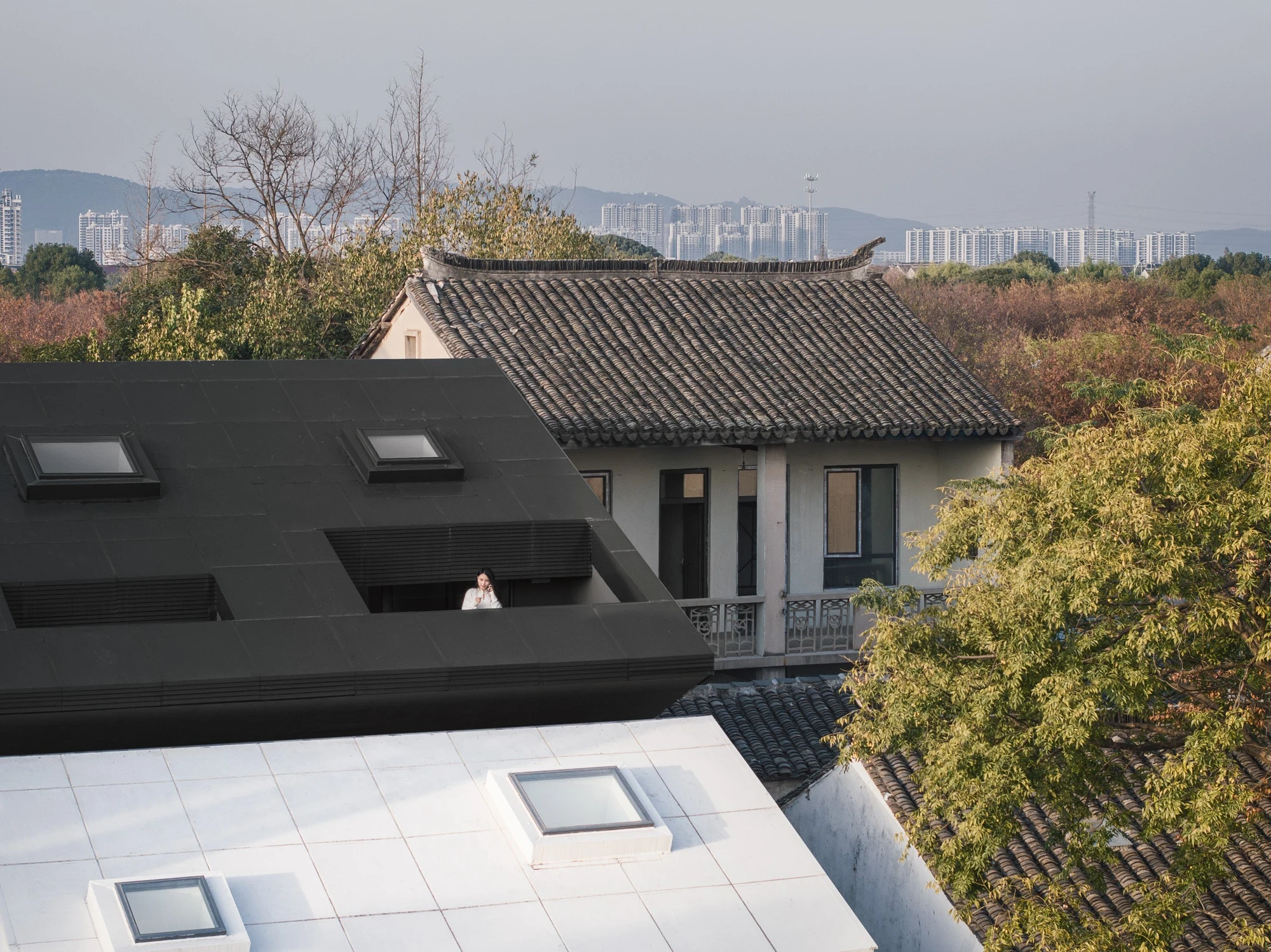 Heart Fields by Wutopia Lab, photographed by CreatAR Images — the black gabled roof nests among grey clay-tiled roofs threaded by a canal and bridge.