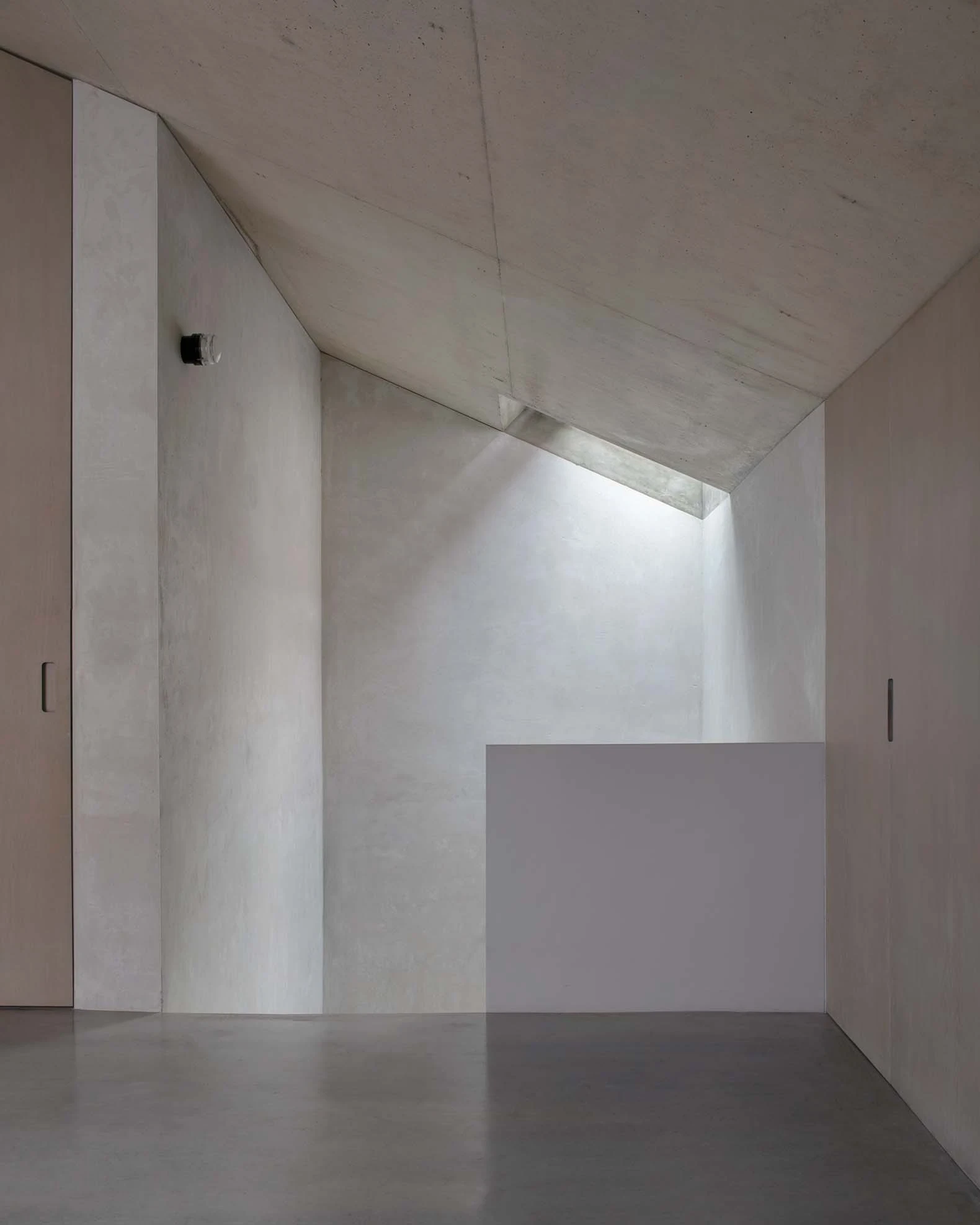 Casa Azul by extrastudio, photographed by Mikael Olsson — a kitchen of brushed steel cabinetry and a solid oak block against grey plaster under a board-marked concrete ceiling.