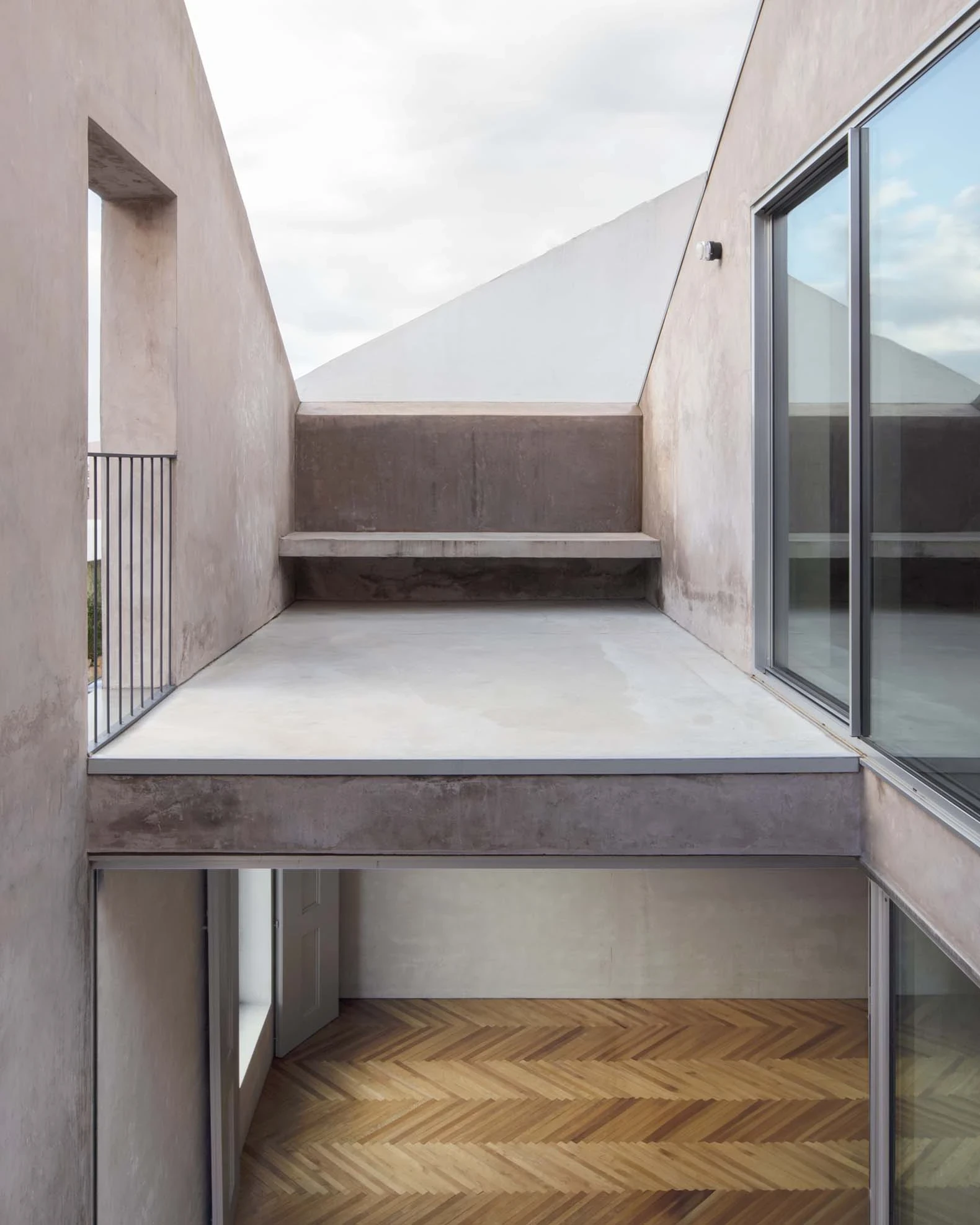 Casa Azul by extrastudio, photographed by Mikael Olsson — herringbone parquet meeting a grey-plastered courtyard through a sliding glass wall.