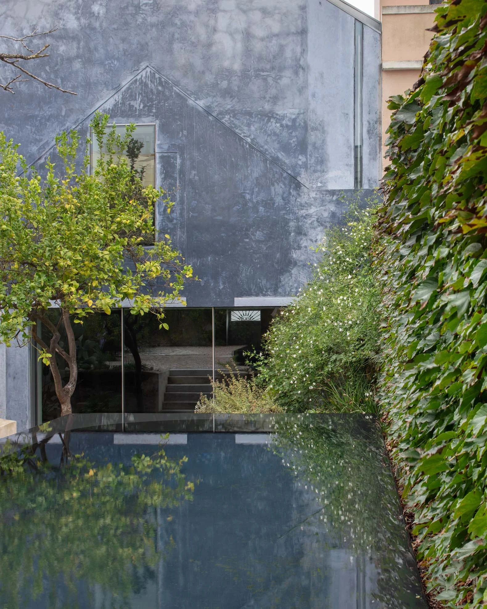 Casa Azul by extrastudio, photographed by Mikael Olsson — the ultramarine lime street facade with panelled front door, dark shutters and gabled roofline set between neighbouring houses.