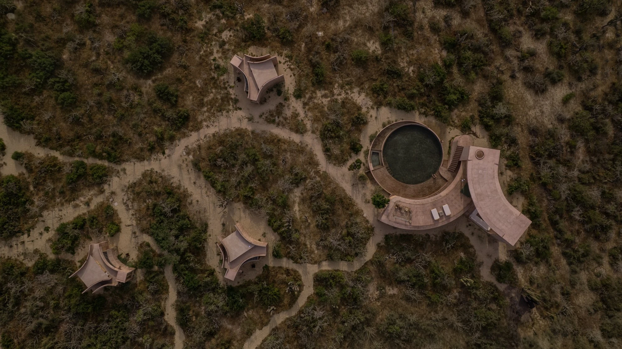 Nereidas by studiofont, photographed by @alberstudio — an overhead view of the shared pavilion and scattered cabins set among desert scrub at dusk.