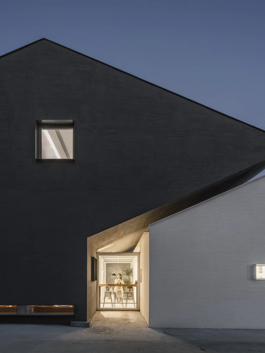 Heart Fields by Wutopia Lab, photographed by CreatAR Images — the twin-gabled black and white elevation of the rural bookstore against grey village roofs.