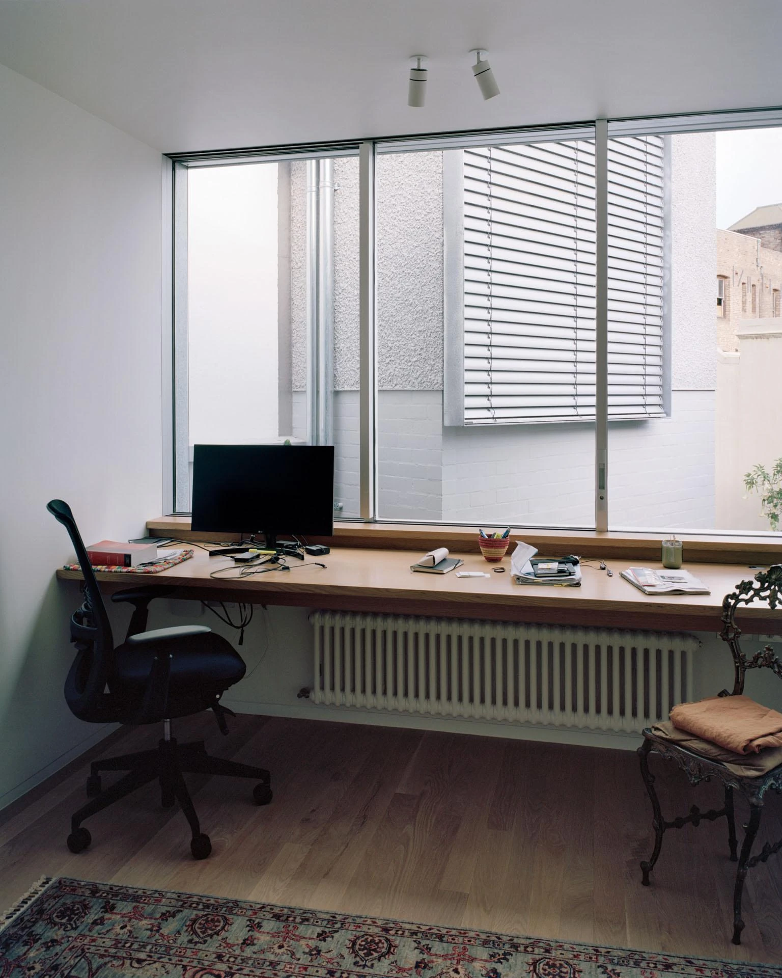 House next to Taylor Square by Anthony Gill Architects, photographed by Rory Gardiner with Colby Vexler — Home office with a long timber sill spanning the window, Venetian blinds, a Persian rug on timber floor.