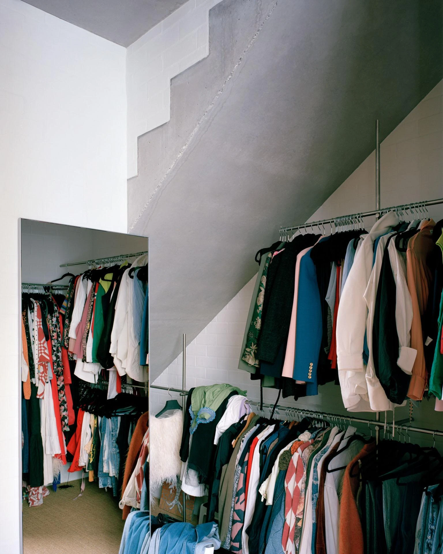 House next to Taylor Square by Anthony Gill Architects, photographed by Rory Gardiner with Colby Vexler — Walk-in wardrobe tucked beneath the concrete stair soffit, clothing rails filling the space under the treads.
