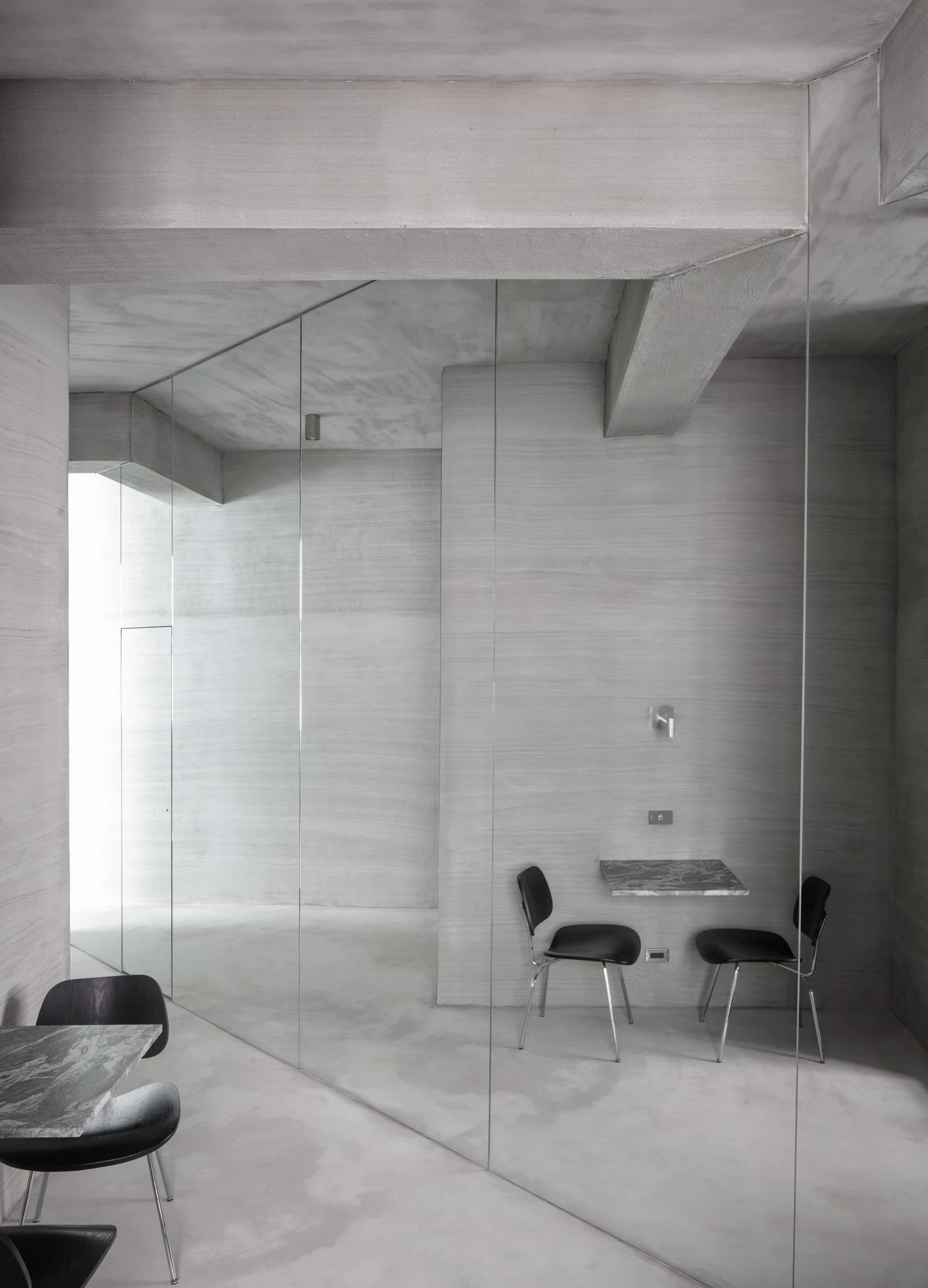 Ximen Apartment by unprofessional.studio, photographed by unprofessional.studio: a wall-mounted grey marble slab and two black moulded-plywood chairs form the dining setting amid infinite mirror reflection.