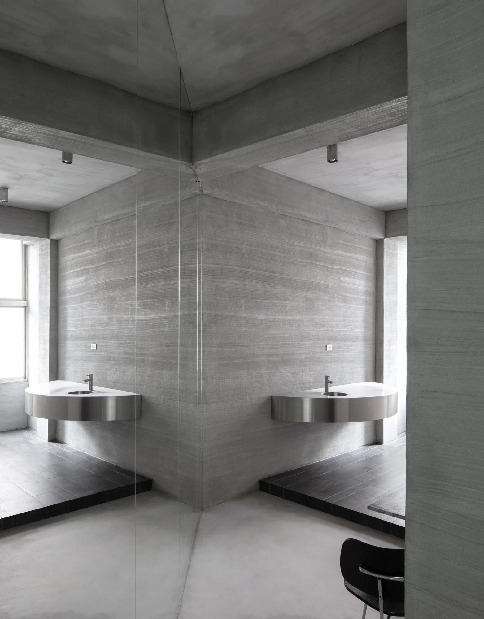 Ximen Apartment by unprofessional.studio, photographed by unprofessional.studio: two rounded stainless steel washbasins hang from the concrete bathroom wall and read as four in the mirror above.
