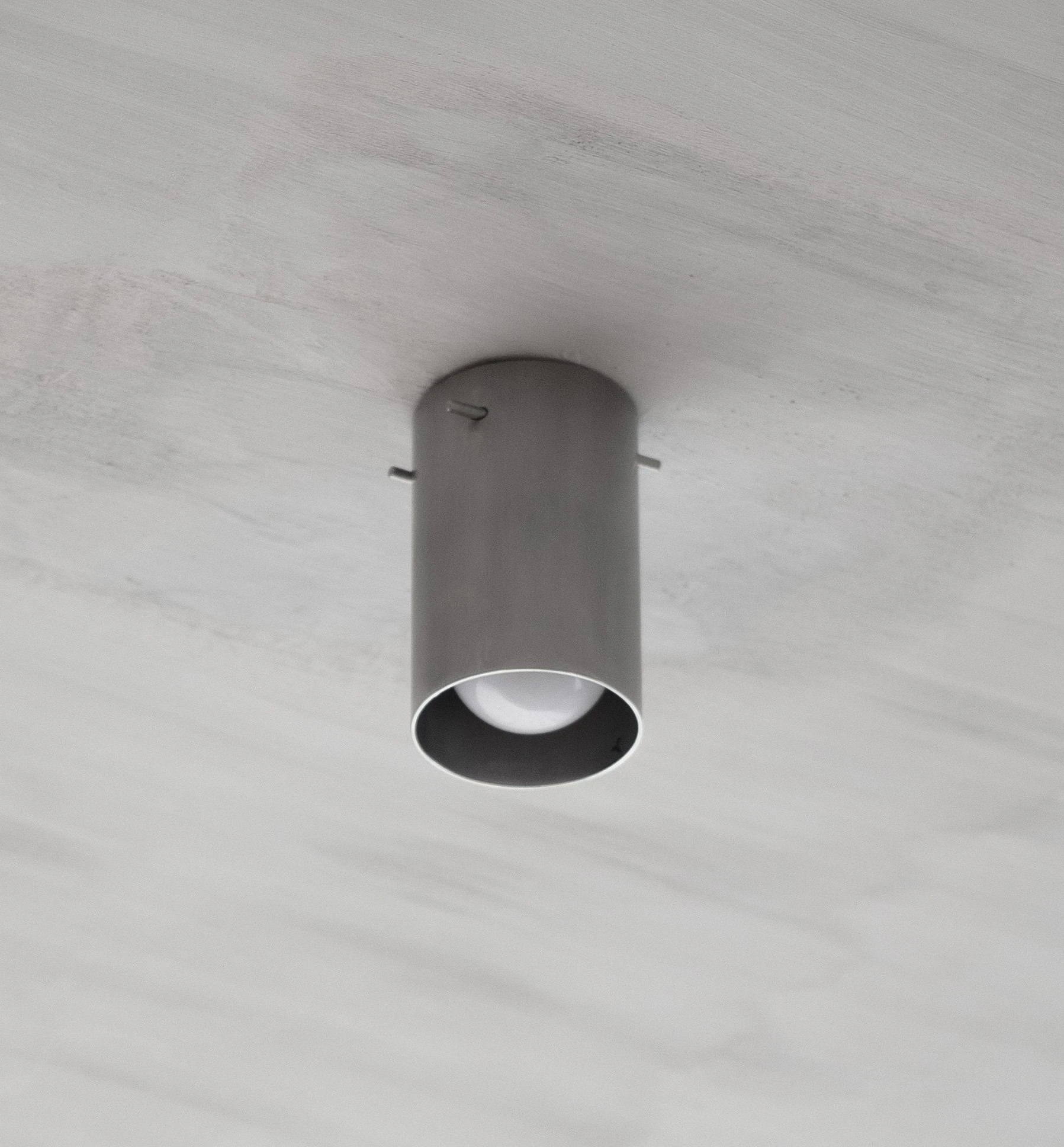 Ximen Apartment by unprofessional.studio, photographed by unprofessional.studio: a single grey cylindrical spotlight set flush into the light-grey concrete ceiling.