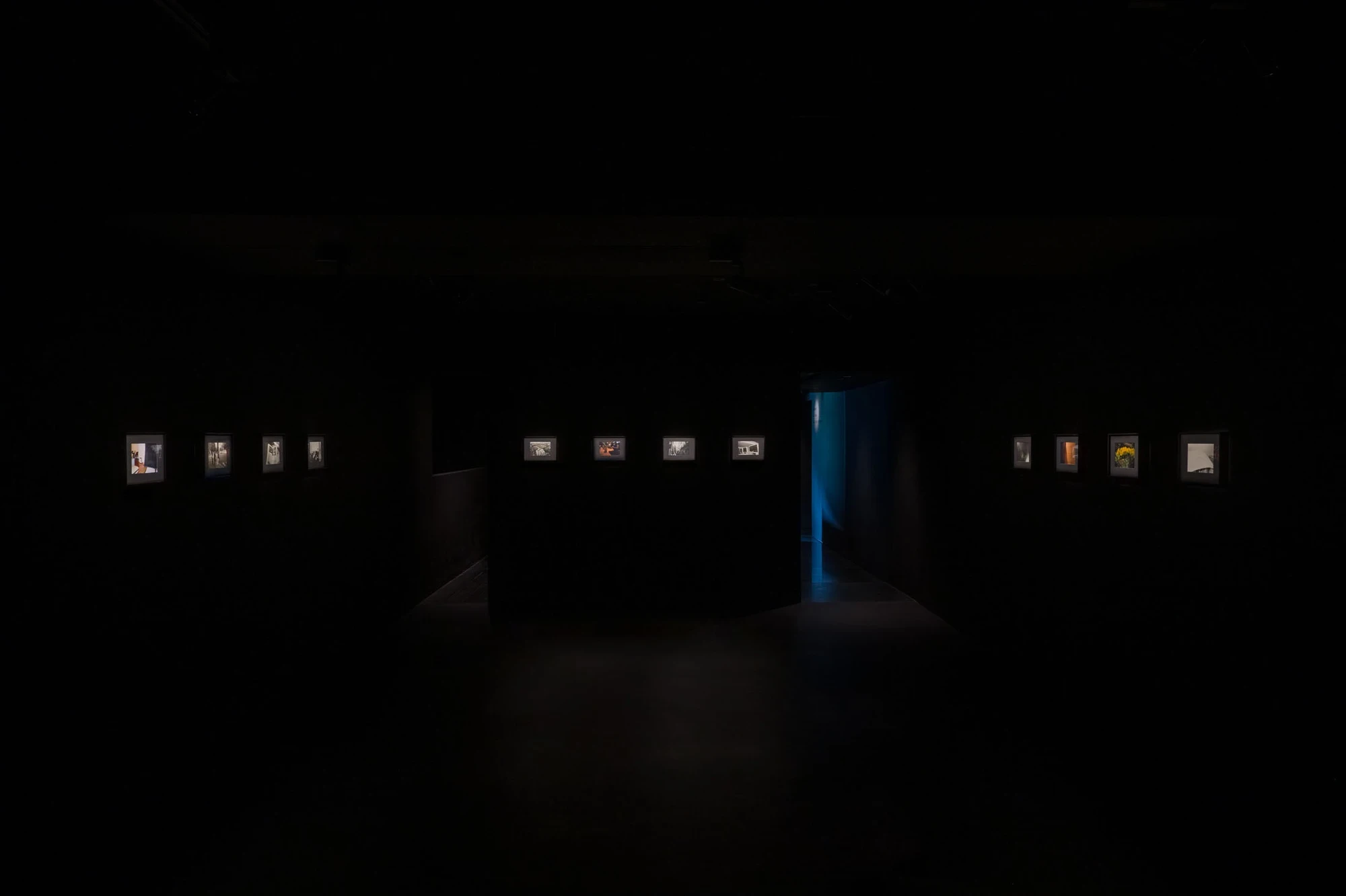 Spillover by Ann Zhao, photographed by Felix S.C. Wong — Framed photographs from Ben Ming Nian glow in a row along a black wall, alternating black-and-white and muted colour images
