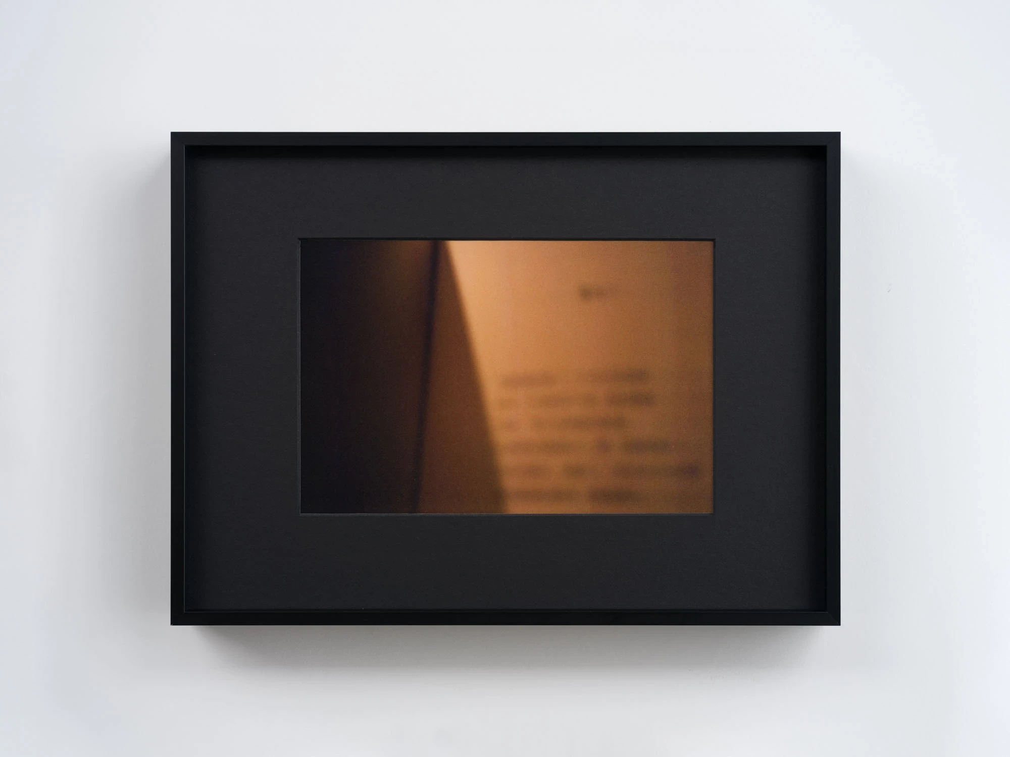 Spillover by Ann Zhao, photographed by Felix S.C. Wong — A warm amber photograph of an out-of-focus page of text catching low light against a dark edge