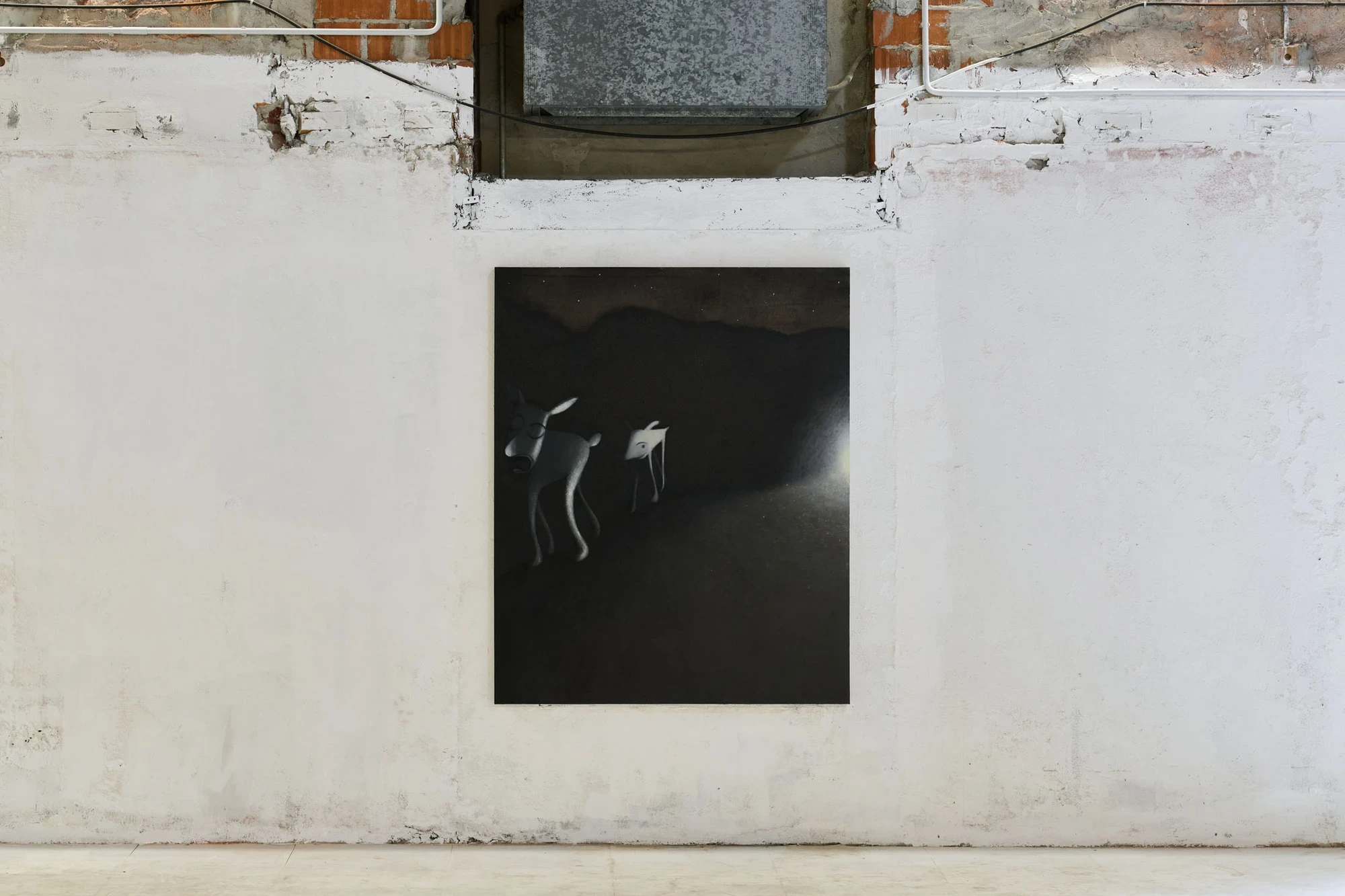 Every Day, Mostly Night, Sometimes Daylight by Satoru Kurata, photographed by Michela Pedranti -- A dark vertical painting of two pale deer-like hybrid creatures moving through black hills hangs alone on a whitewashed wall below a metal duct and a band of