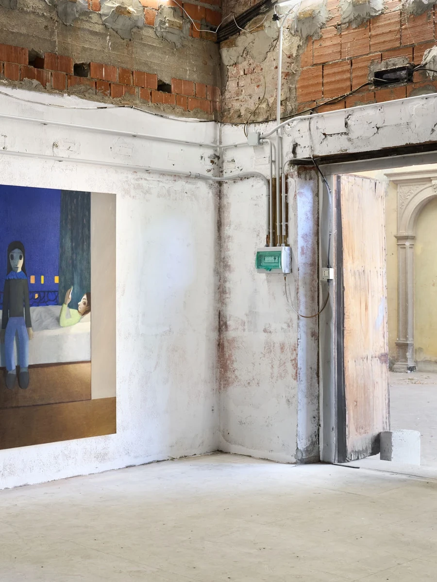 Every Day, Mostly Night, Sometimes Daylight by Satoru Kurata, photographed by Michela Pedranti -- A tall canvas of a night bedroom, a standing blue-clad figure and a second figure lying on the bed lit by a phone, hung on whitewashed plaster beneath a jagg