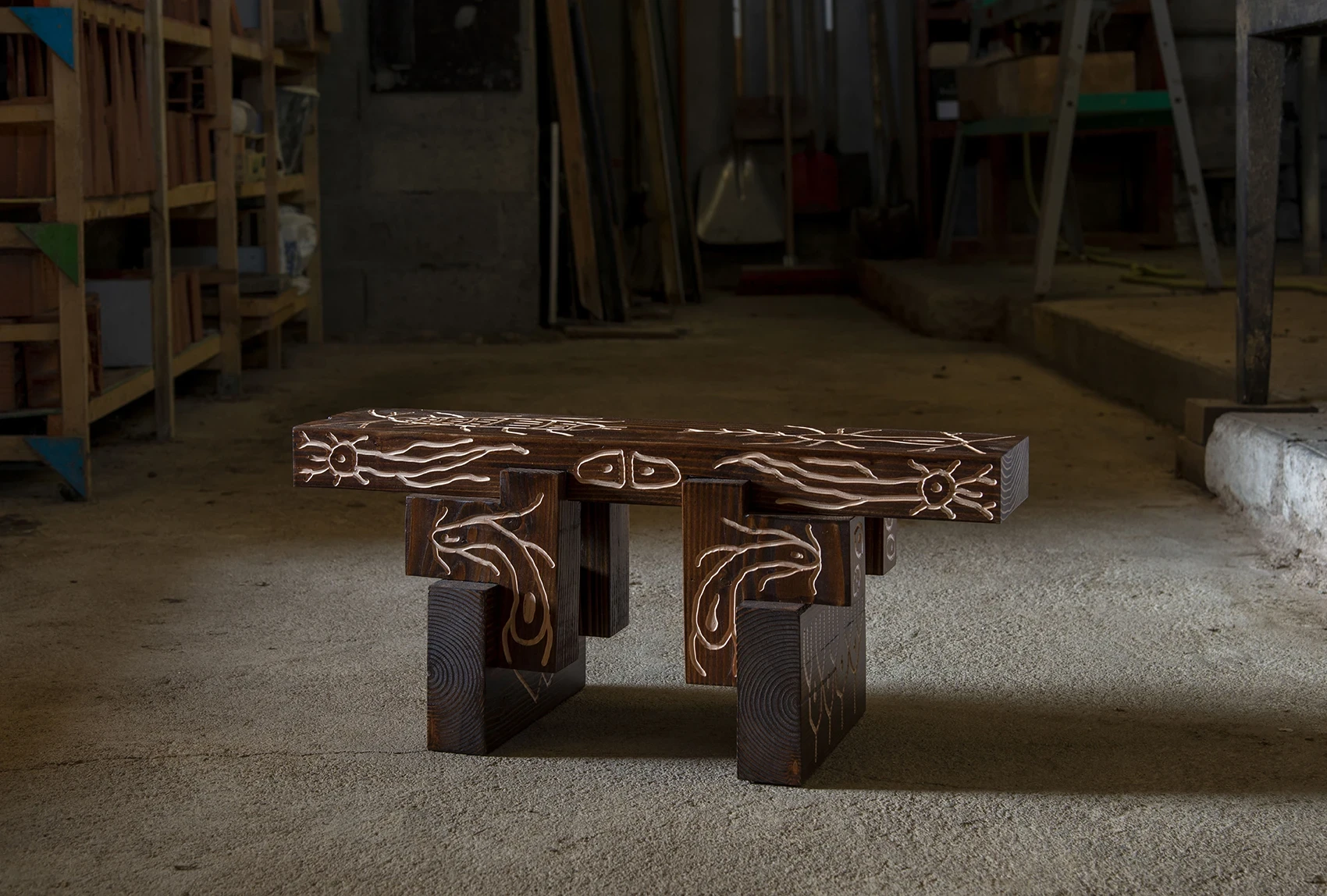 Les Rhizopodes by Barreau Charbonnet — A low bench shown in full, a beetle, suns and hands carved along the beam and filled pale cream