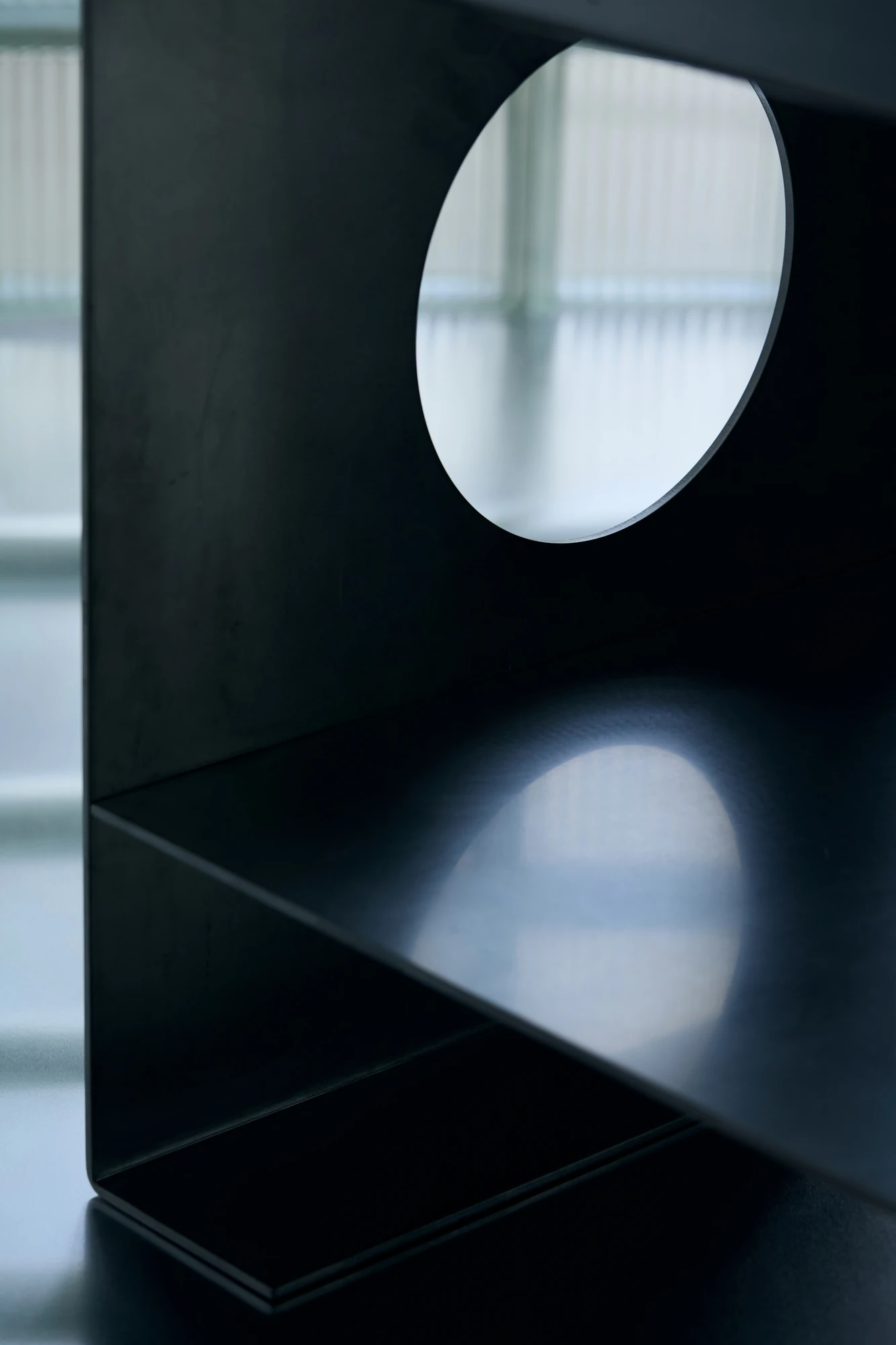 010 Aluminium Lounge Chair by OFAA, photographed by @spaceblank, @aura.photography — The circular aperture cut through the aluminium side panel, seen close and lit from behind.