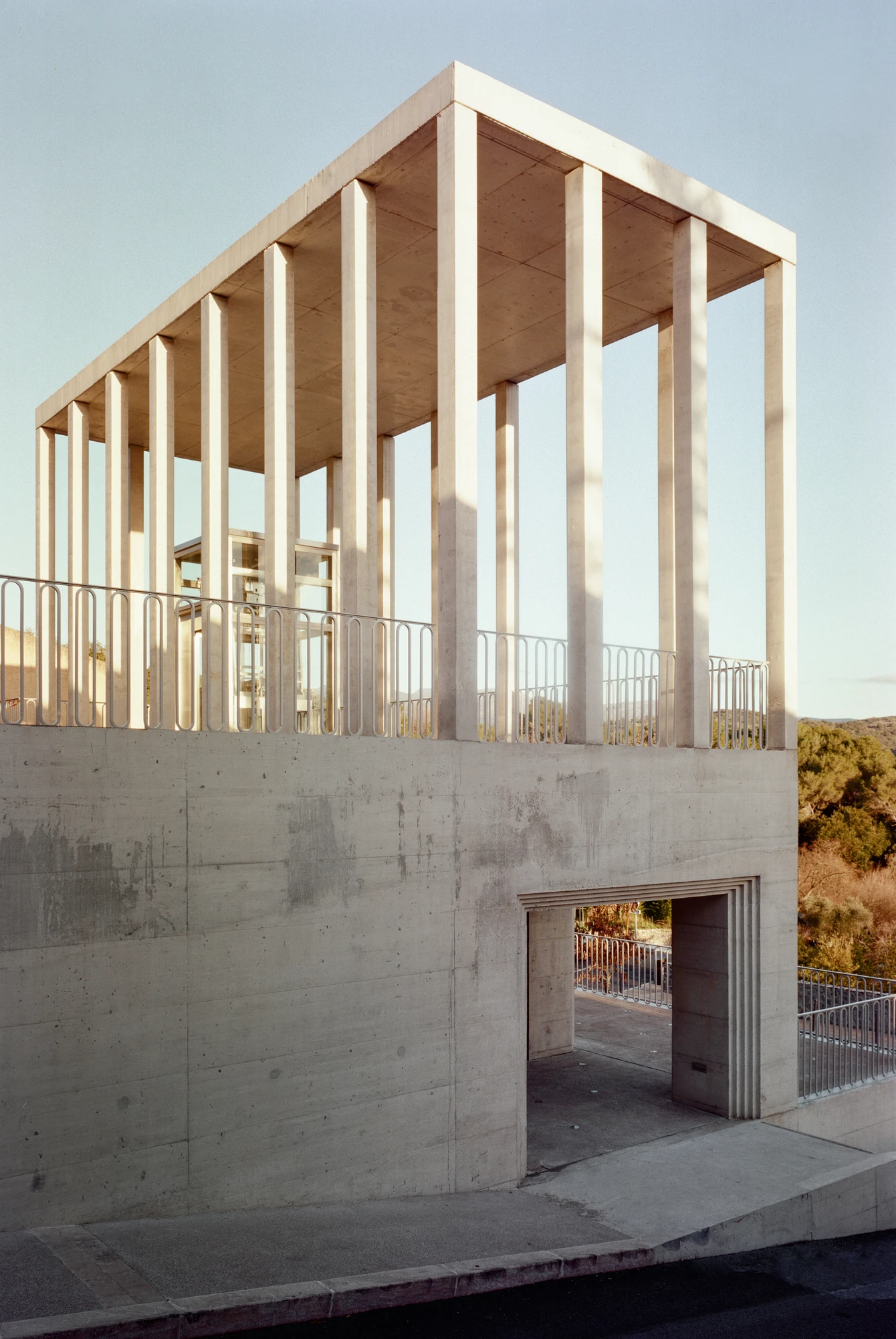 Biot Municipal Building Extension by Atelier EGR, photographed by Giaime Meloni — Corner of the building where the blank concrete wall meets the columned level, an opening cut with stepped reveals below.
