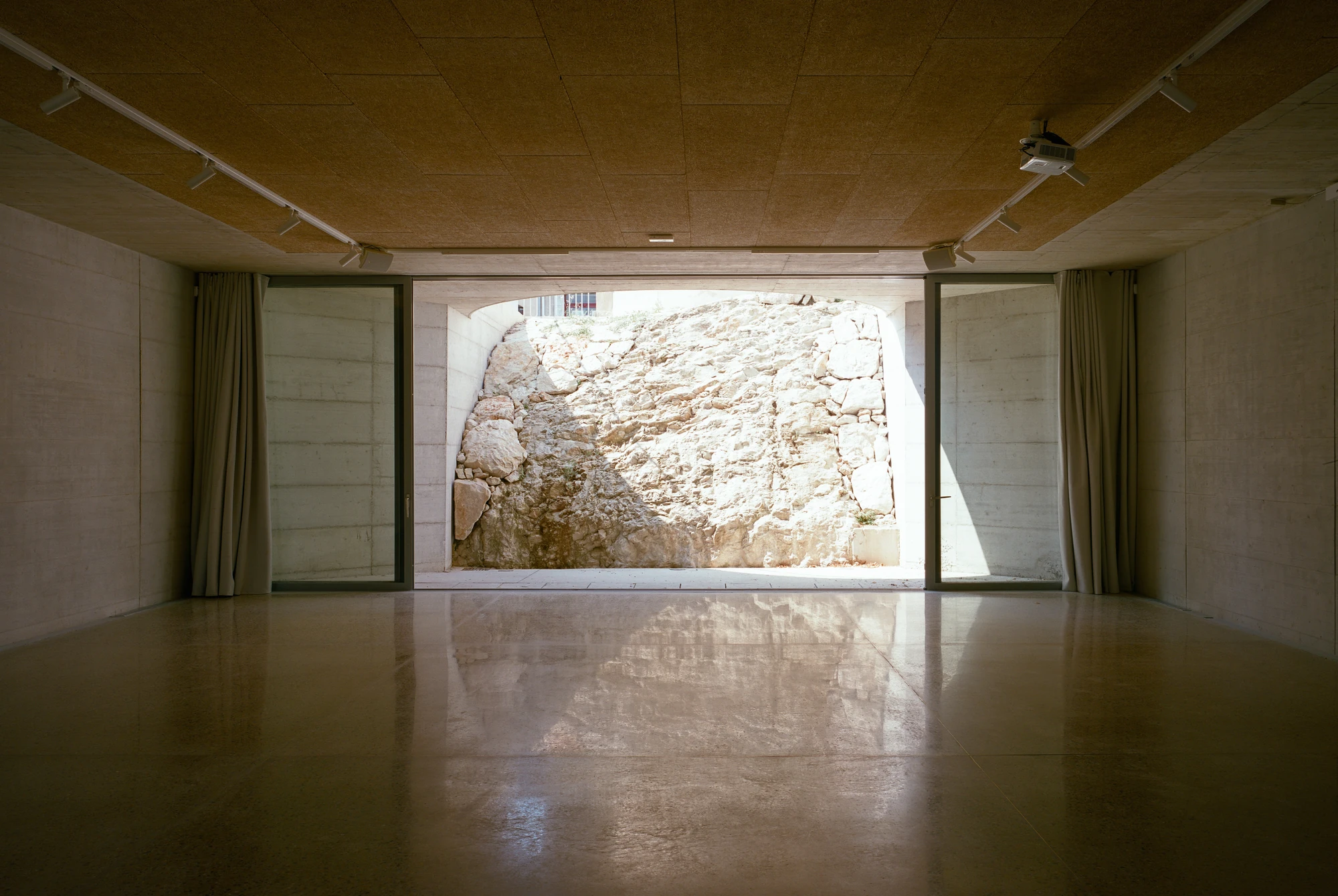 Biot Municipal Building Extension by Atelier EGR, photographed by Giaime Meloni — The meeting room, terrazzo floor and panelled ceiling, opening through full-height glazing onto a patio of raw limestone.