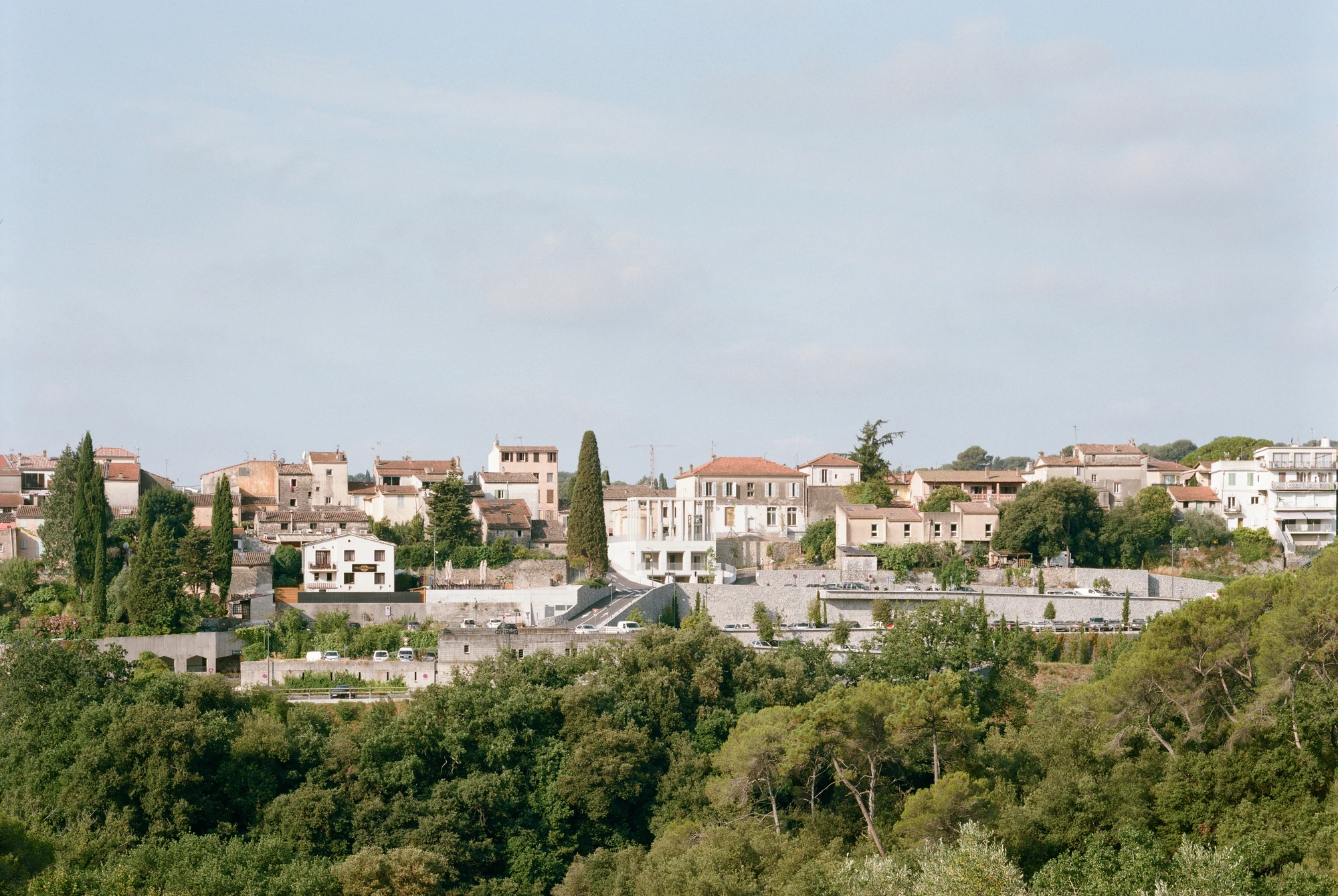 Biot Municipal Building Extension by Atelier EGR, photographed by Giaime Meloni — Distant view of Biot on its ridge, the pale extension visible among the tiled roofs of the historic centre.