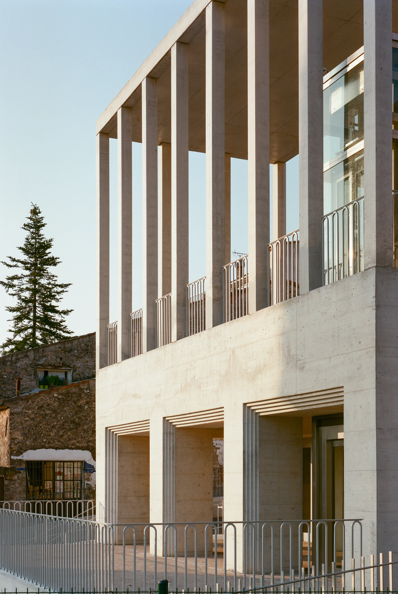 Biot Municipal Building Extension by Atelier EGR, photographed by Giaime Meloni — Three deep openings with stepped reveals at the lower level, the columned terrace and glazed lift above them.