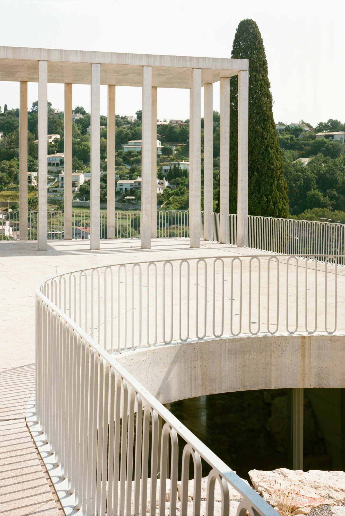 Biot Municipal Building Extension by Atelier EGR, photographed by Giaime Meloni — The curved balustrade on the deck, wrapping a void that drops to the glazed room and the rock below.