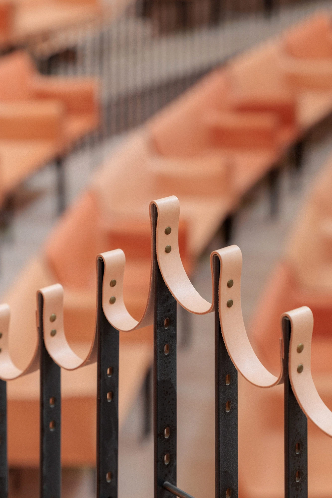 La Source Vive by PCA-Stream, photographed by PCA-Stream — Detail of undyed leather loops riveted to perforated black steel rails in front of the seating.