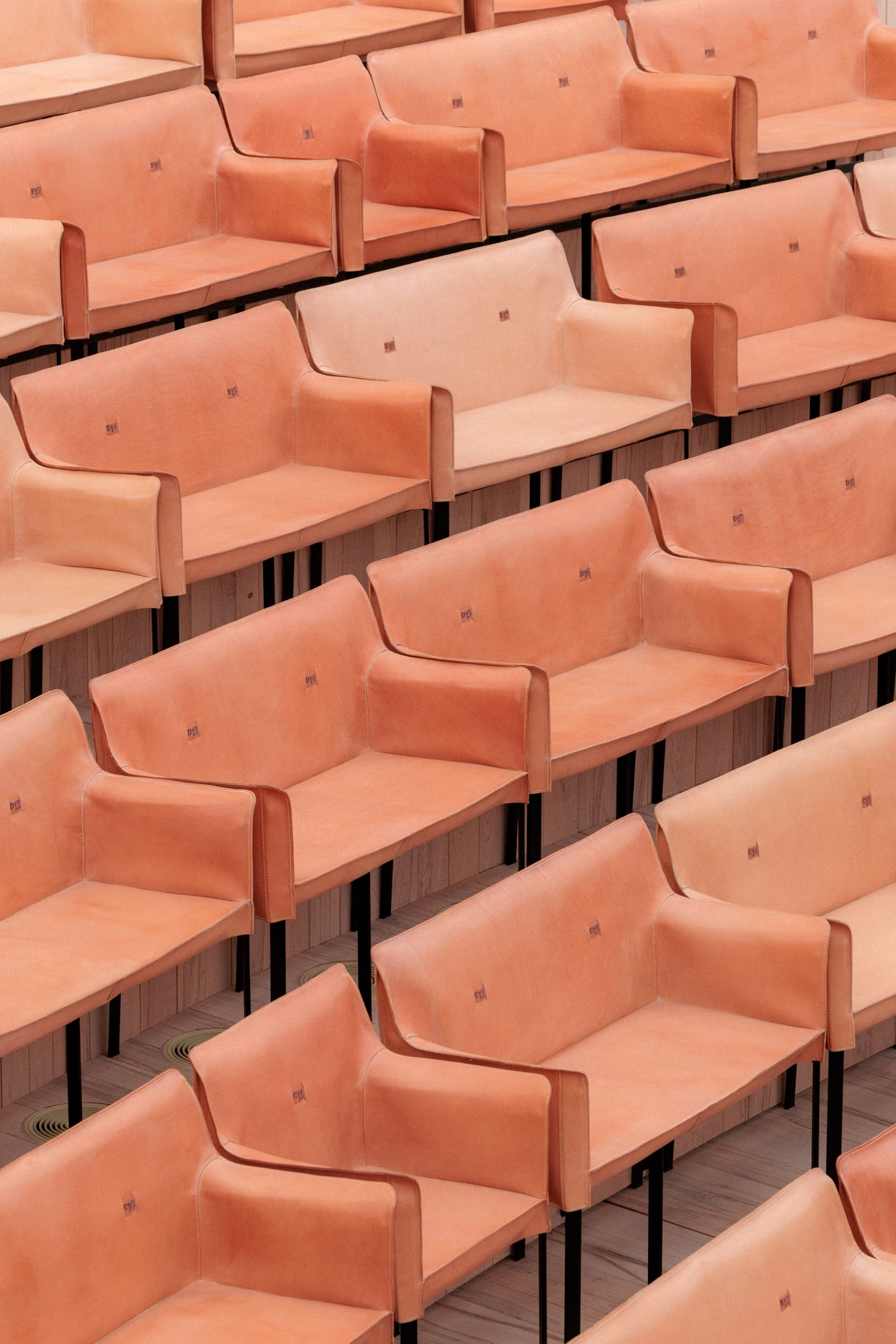 La Source Vive by PCA-Stream, photographed by PCA-Stream — Overhead view of the leather benches, each stamped with a row and seat number, carried on slim black steel legs.
