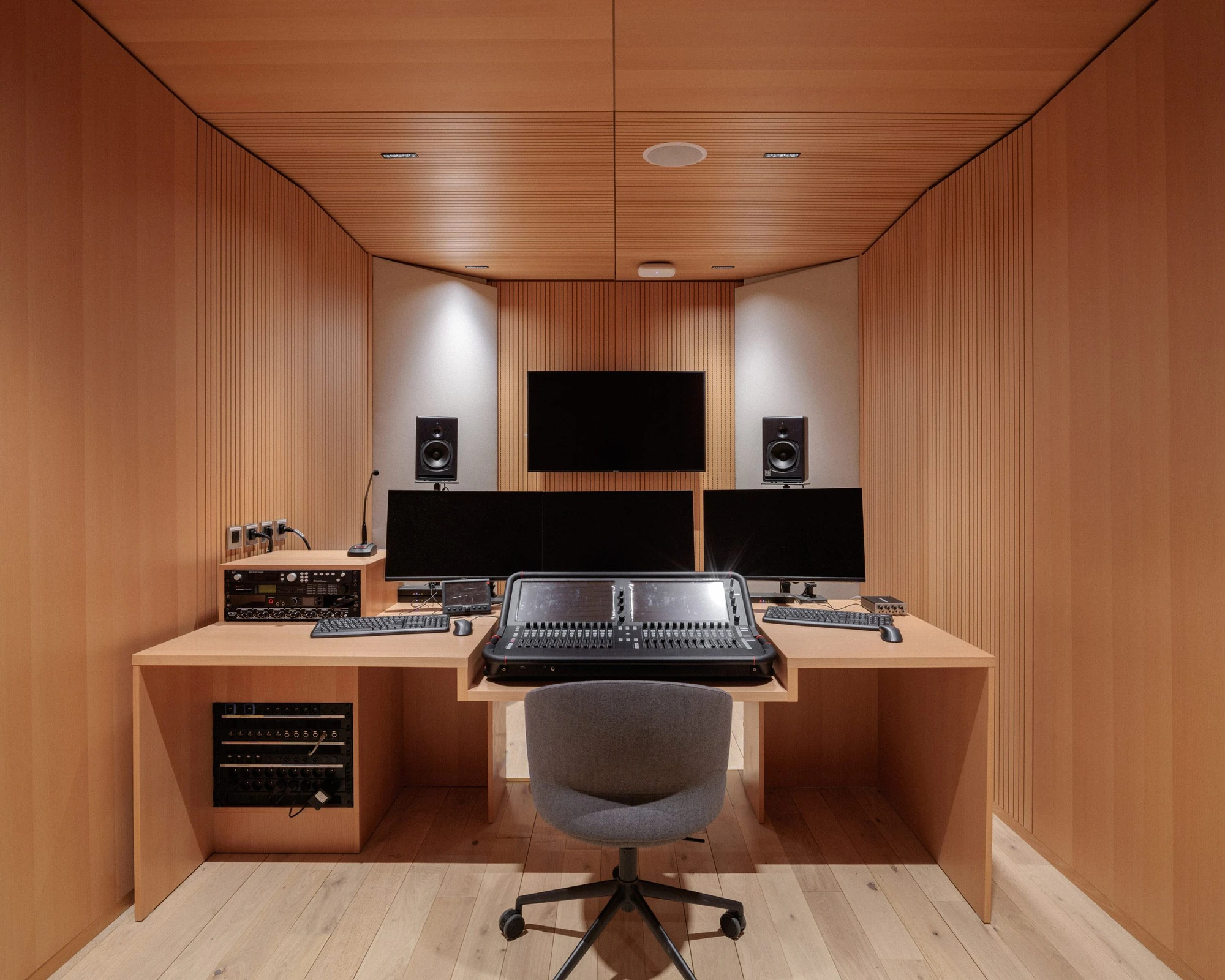 La Source Vive by PCA-Stream, photographed by PCA-Stream — Recording control room lined in vertical timber battens, with a mixing desk, monitors and studio speakers.
